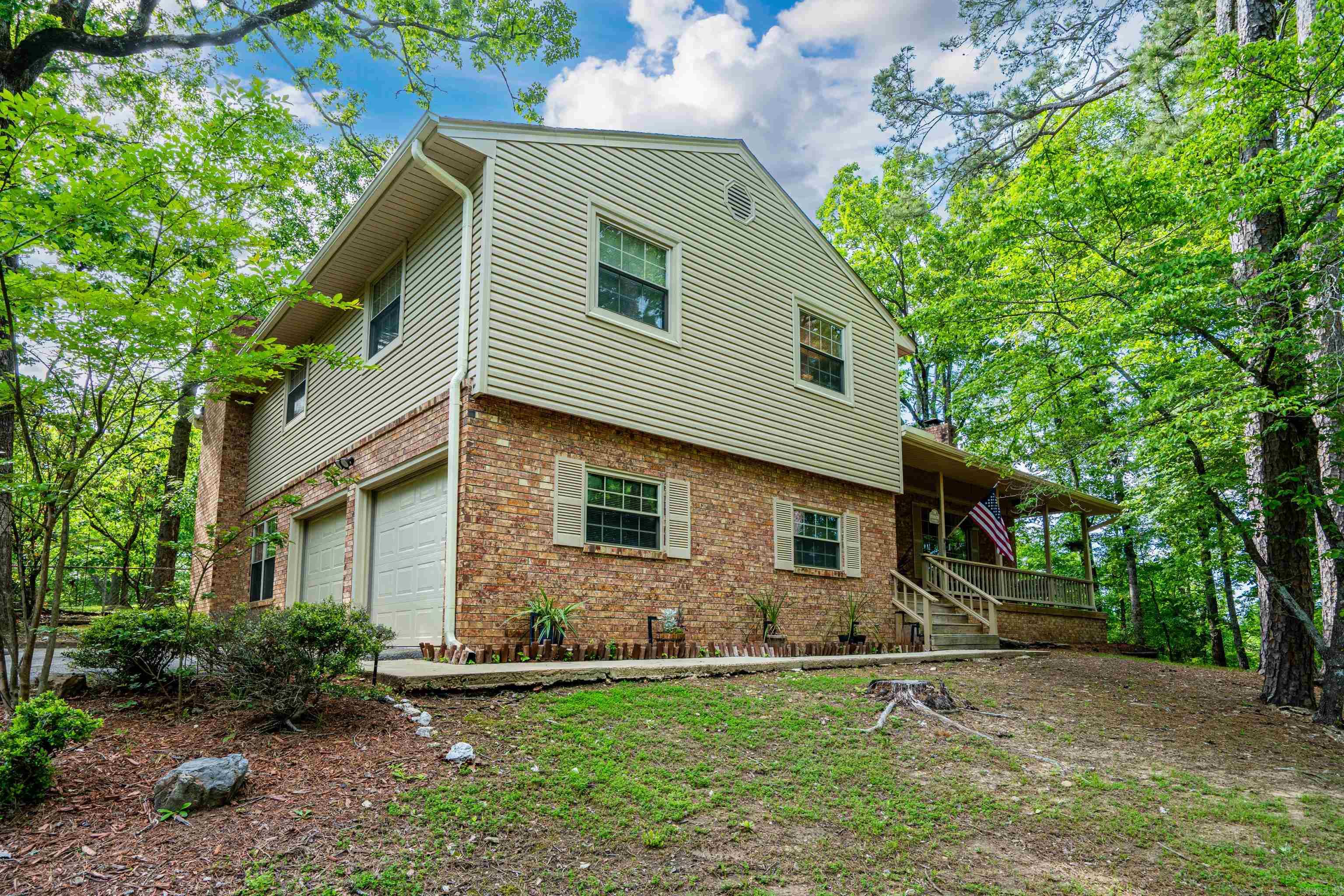 Private 6.28 acres just minutes from Hot Springs-the rare combination of space, privacy and peaceful country living. Enjoy quiet mornings on the welcoming front porch, taking in the natural surroundings. This 2,612 sq. ft. home features 3 bedrooms plus a flexible den currently used as a 4th bedroom. The lower-level den offers a private retreat with a stone wood-burning fireplace, full bath and garage access-ideal for guests or extended living.   The main level includes a bright living room with a large picture window and brick fireplace, flowing into the dining area for a layout that feels both connected and defined. The kitchen features granite countertops, bamboo flooring, custom cabinetry and ample storage.   Step outside to a 20 x 32 patio with pergola, ceiling fan, lighting and custom railing. This outdoor living area overlooks a fully fenced-backyard. and is surrounded by woods on three sides-a peaceful setting where you can often enjoy local wildlife. The home is wired with ethernet for your office needs. Two car garage. Privacy, flexibility and room to spread out-all just minutes from Hot Springs.