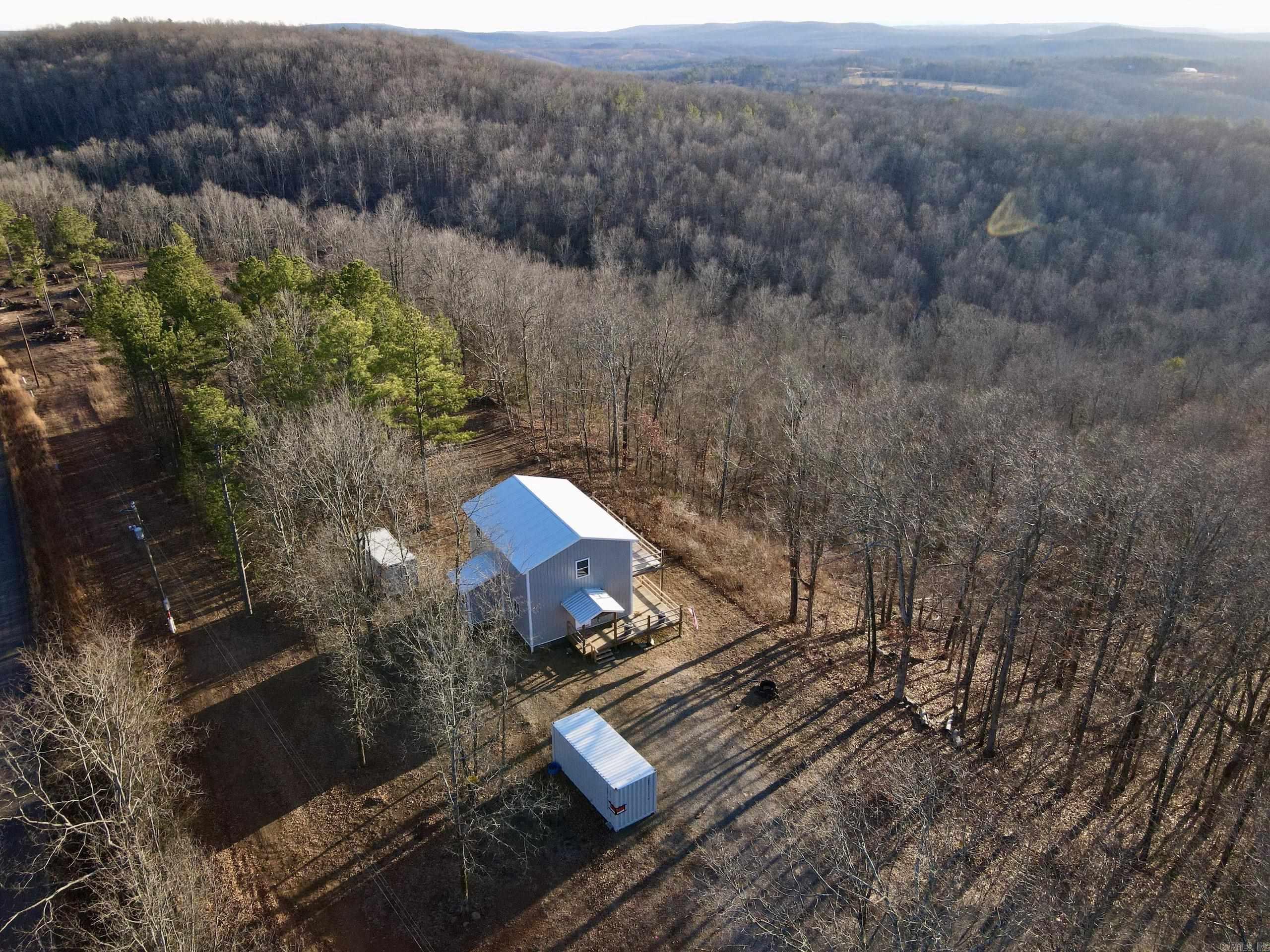 If you have been looking for a nice secluded home on acreage that won't break the bank, then you might want to take a look at this one. This approximately 1600 sq. ft. two-story, three bed two and a half bath home has paved county road frontage with rural water, electricity and high-speed internet. The main bedroom is on the lower floor and has a nice dual vanity with a walk-in shower. The kitchen has an electric range, dishwasher and pantry. Just off the kitchen is a laundry room with a half bath. Upstairs are two bedrooms and a full bath with a nice sitting area that opens to a large deck perfect for watching the soaring views and stunning sunsets. In fact, when you combine the upper and lower decks, there is nearly 575 sq. ft. of deck that adds to the space you can use. The property has a nice stand of young timber and is home to abundant wildlife, including deer, bear and turkey. Hike along the trails or walk the graveled road that wonders across the property and explore the rock ledge and the beautiful seasonal waterfall. There is one storage container that will convey. This property checks a lot of boxes and is really worth taking a look at. Call to schedule a showing.
