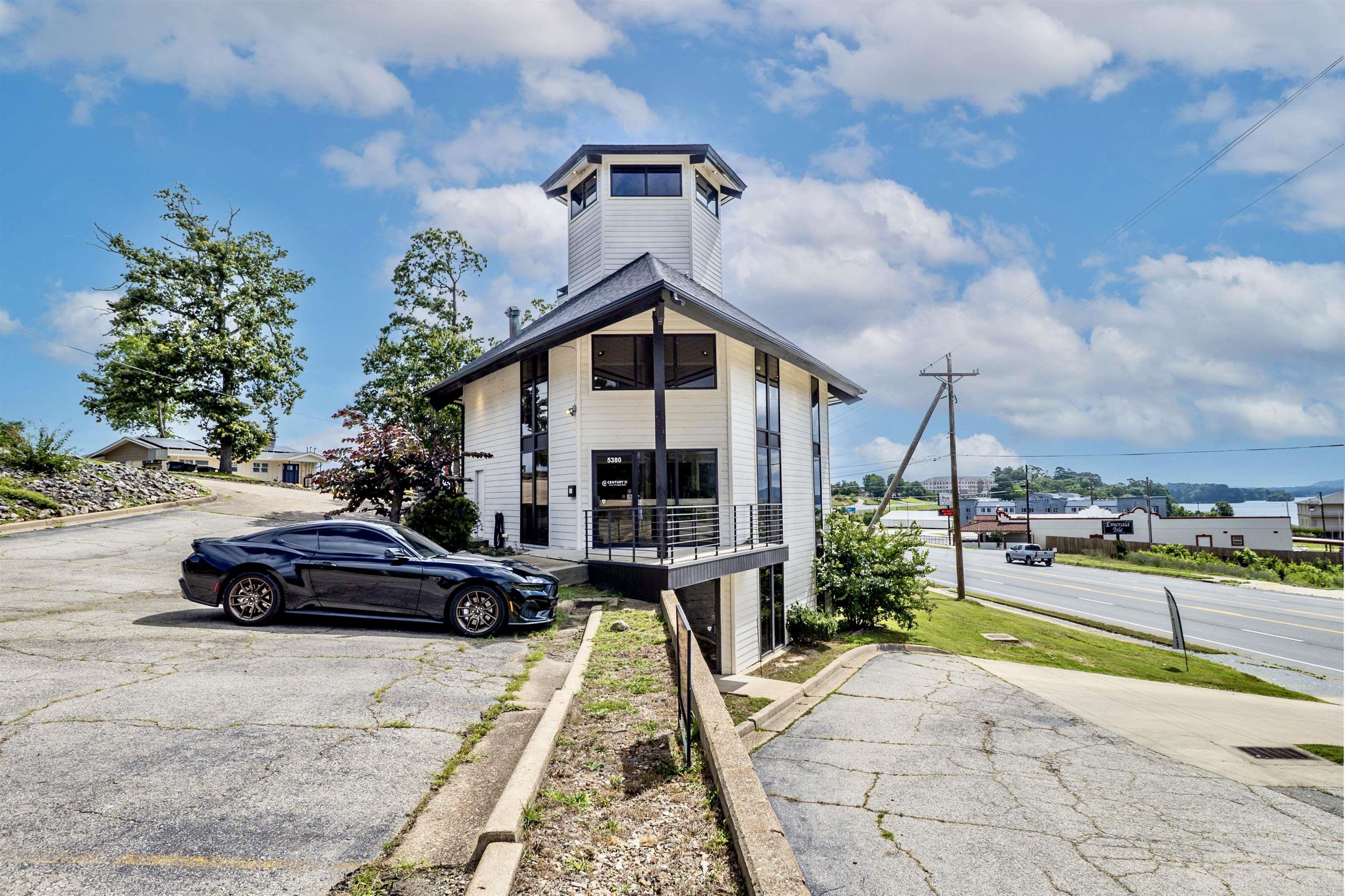 Prime commercial opportunity on Central Avenue in Hot Springs! This 5-level contemporary building offers exceptional visibility, high traffic exposure, & Highway Commercial zoning. Featuring dual access from Central Avenue and Hamilton Oaks Drive plus a prominent display sign at the corner, your business will enjoy maximum exposure. The main covered entrance opens to a stunning reception area with soaring ceilings, expansive windows, & abundant natural light. Built-in desks, cabinets, counters, & extensive storage are found throughout, with kitchen areas on every level. Enjoy two covered walkout patios overlooking Lake Hamilton & a fourth-level tower with breathtaking panoramic views. The lower level has separate exterior access from the parking lot, ideal for multiple uses. Four bathrooms, including a full bath, Central Alarm system, engineered wood flooring, ceramic tile, & carpeted stairs complete the interior. Approximately 7,048 sq. ft. of paved parking & provide ample parking, with lower-level parking connecting to the main entry level. Conveniently located near retail, restaurants, & all the amenities of Central Avenue, this one-of-a-kind property is ready for your business!