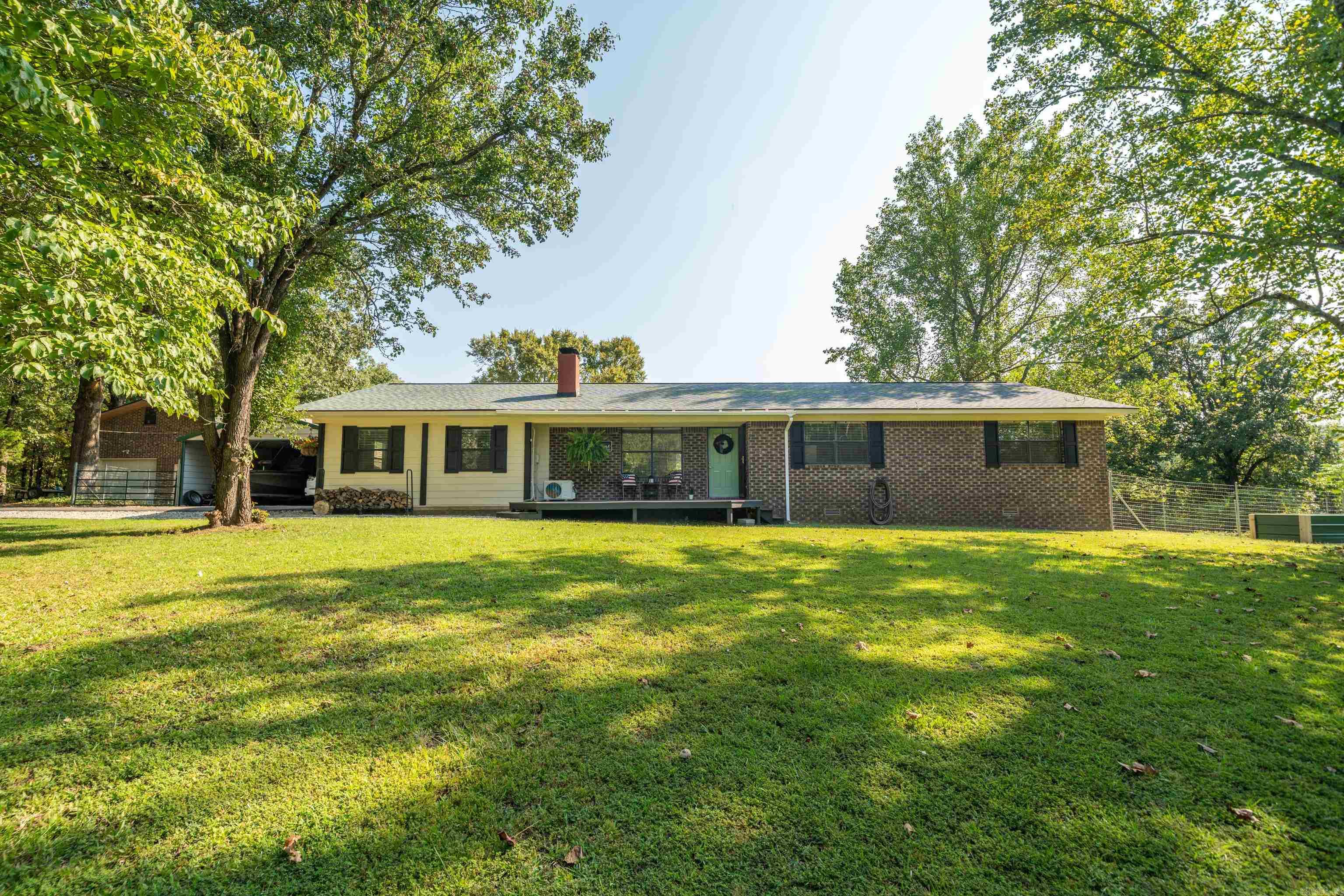 STEP INTO PARADISE just two miles from town and 10 minutes to a Lake Hamiltom public boat launch.  Set on three plus gated acres, fully fenced acres with mature hardwoods and open pasture—ideal for livestock or hobby farming. Move-in ready 4BR/2BA home with standout amenities: 600 sq ft brick shop (water, sink, electric) plus 600 sq ft loft with high ceilings, and an attached barn with stalls, water, lighting, fan, and new roof. Extras include chicken coop, tractor shed, and a private 92’ well with backup hand pump. Major upgrades: new roofs on all structures (2023), composite decks (2023–2024), trim paint (2024), shutters (2025), and updated fixtures. Versatile, well-equipped, and ready to go—rare value this close to town.