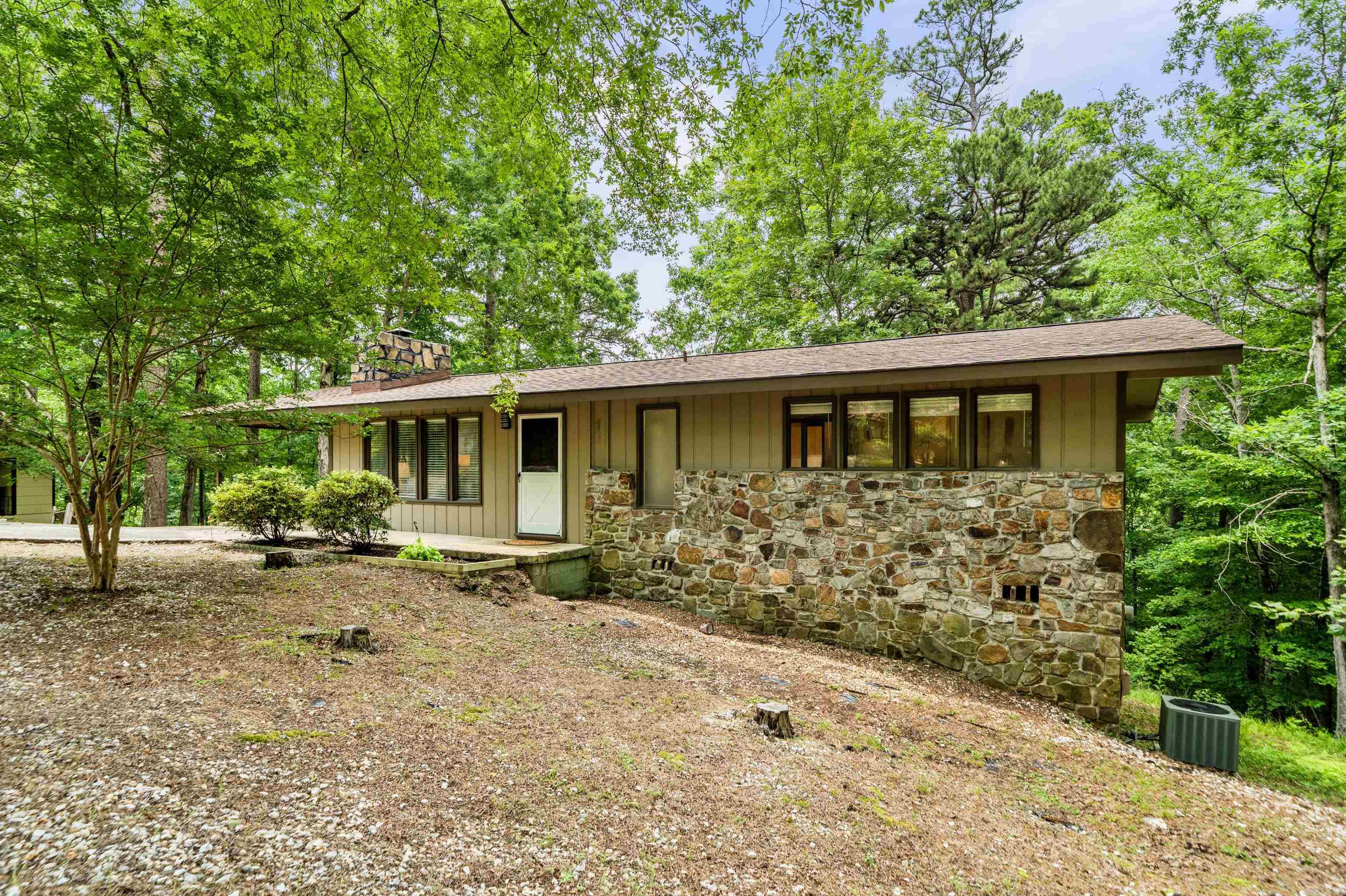 Nestled in the trees of Hot Springs Village, this 3-bedroom, 3-bath home offers a unique layout with two separate living areas, making it perfect for guests, multigenerational living, or added privacy. The main level features a spacious living room with fireplace, dining area, full kitchen, and primary suite, while the lower level includes its own living space, kitchenette, bedroom, bath, and laundry area.   Brand new roof, dishwasher and stove, carpeting and insulation - this home is move in ready!!   Enjoy the peace and privacy of a wooded setting while taking advantage of the lakes, golf, trails, and amenities that make Hot Springs Village such a sought-after destination.