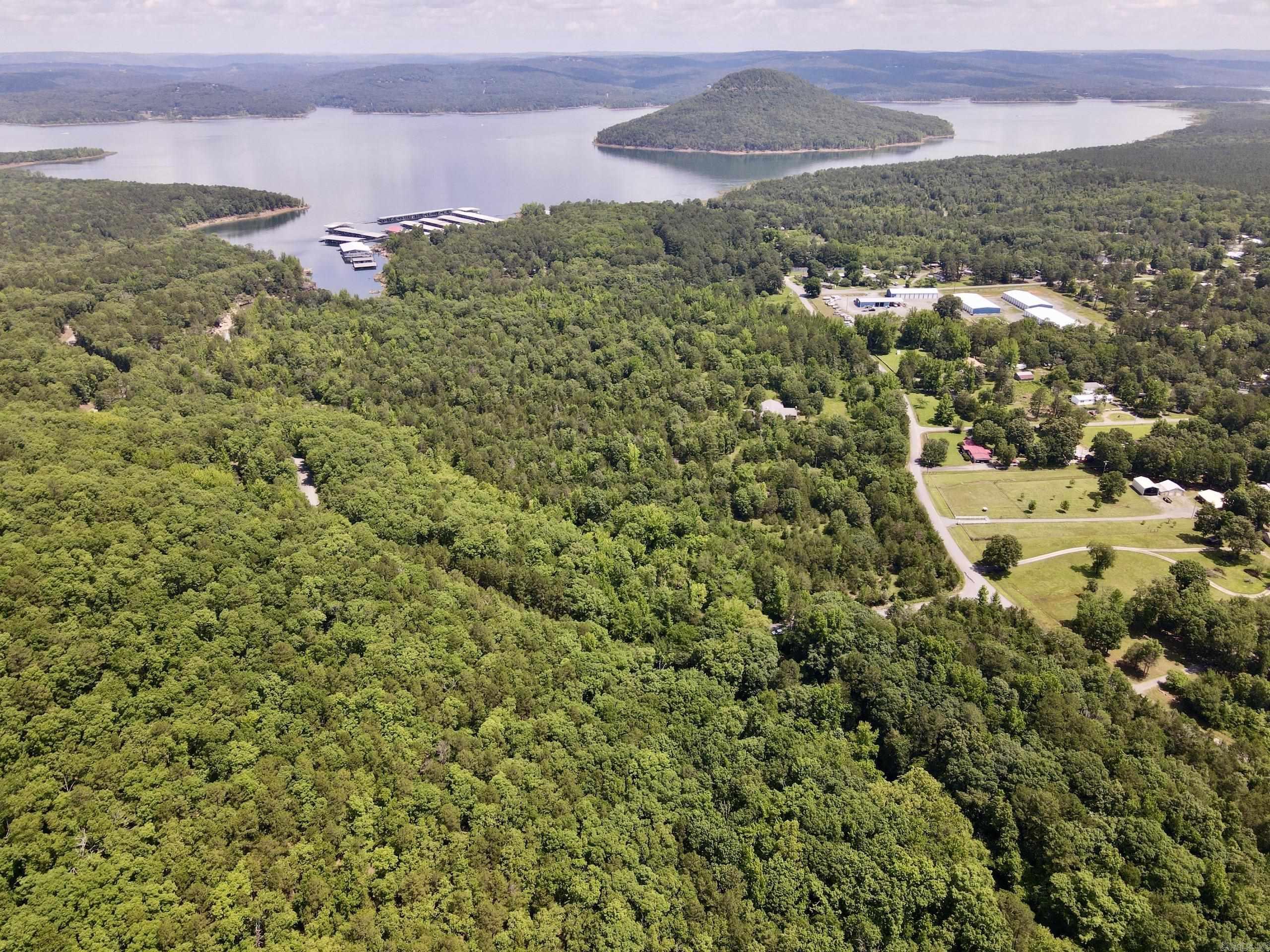 Discover one of the most unique lake-area properties near Greers Ferry Lake. Located at the corner of two county roads, this exceptional tract is just ¼ mile from Sugar Loaf State Park and ¾ mile from Sugar Loaf Marina and boat launch, providing quick access to some of Arkansas’ best boating, fishing, and recreation.  A standout feature is Lazy Creek, a year-round creek that flows through the property before entering Greers Ferry Lake. Mature hardwoods line the creek, creating a scenic, park-like setting with shaded pools and flowing water.  The land rises approximately 180 feet in elevation, offering multiple premium building sites with panoramic views of Greers Ferry Lake, Sugar Loaf Mountain, and Sugar Loaf Marina. These elevated homesites are ideal for a custom lake home, cabin, family retreat, or investment property.  Located in the Ozark Mountains of north-central Arkansas, the property features county road frontage on two sides, nearby utilities, and easy access to hiking, marinas, and lake recreation.  Properties offering year-round creek frontage, lake views, multiple building sites, and close proximity to Sugar Loaf and Greers Ferry Lake are extremely rare.
