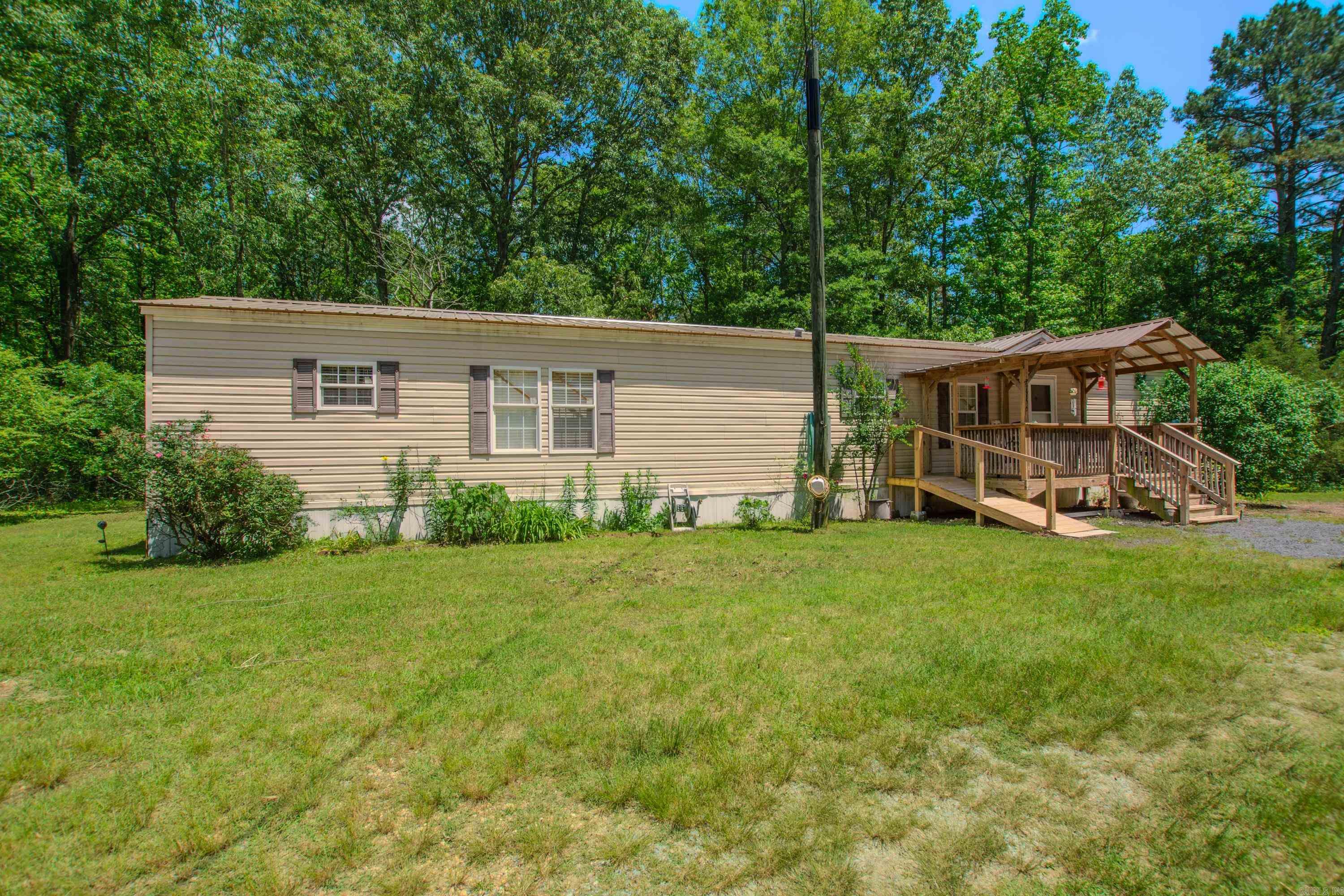 If you are looking for privacy and land to have room to spread  out, this is a great place.  3 bd 2 ba mobile home with front and back porches. Spacious kitchen.  Large family room open to kitchen and dining.  Pantry and laundry combination.  Brand new metal roof. Extra slab for 2200 sf home on site. Extra septic. Property is located off South Sardis.  Turn at mailbox at sign and drive to back of property. Survey on file.