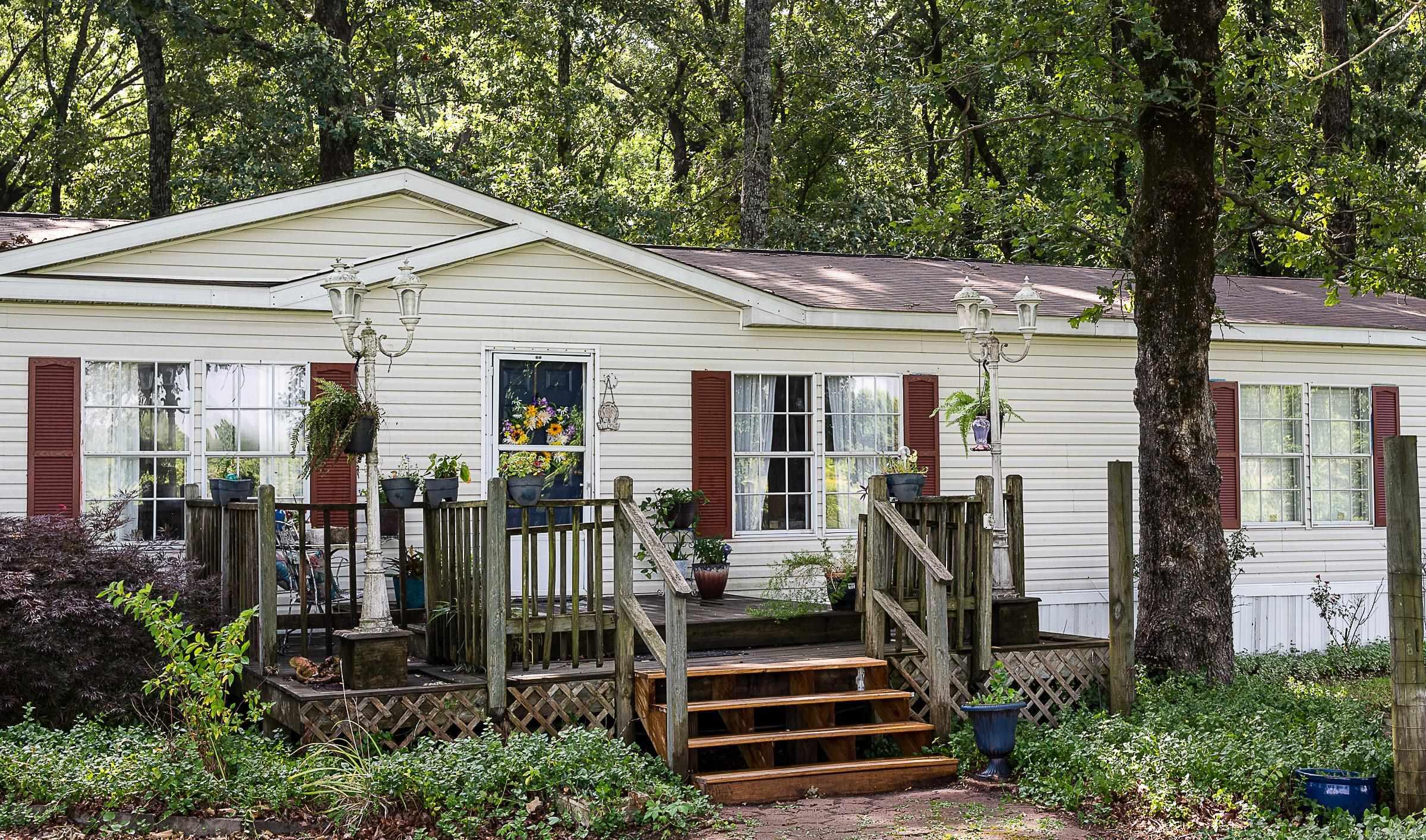 Enjoy peaceful country living in this 3-bedroom, 2.5-bath home situated on 6 acres outside the city limits. Over half the property is cleared and fenced, complete with a hay barn, while the wooded area surrounding the home provides plenty of shade and privacy. This double-wide manufactured home sits on a permanent foundation and qualifies for most financing. With just a little TLC, this property offers incredible potential and has been priced accordingly. Perfect for those looking for acreage, room for animals, or a quiet country setting.