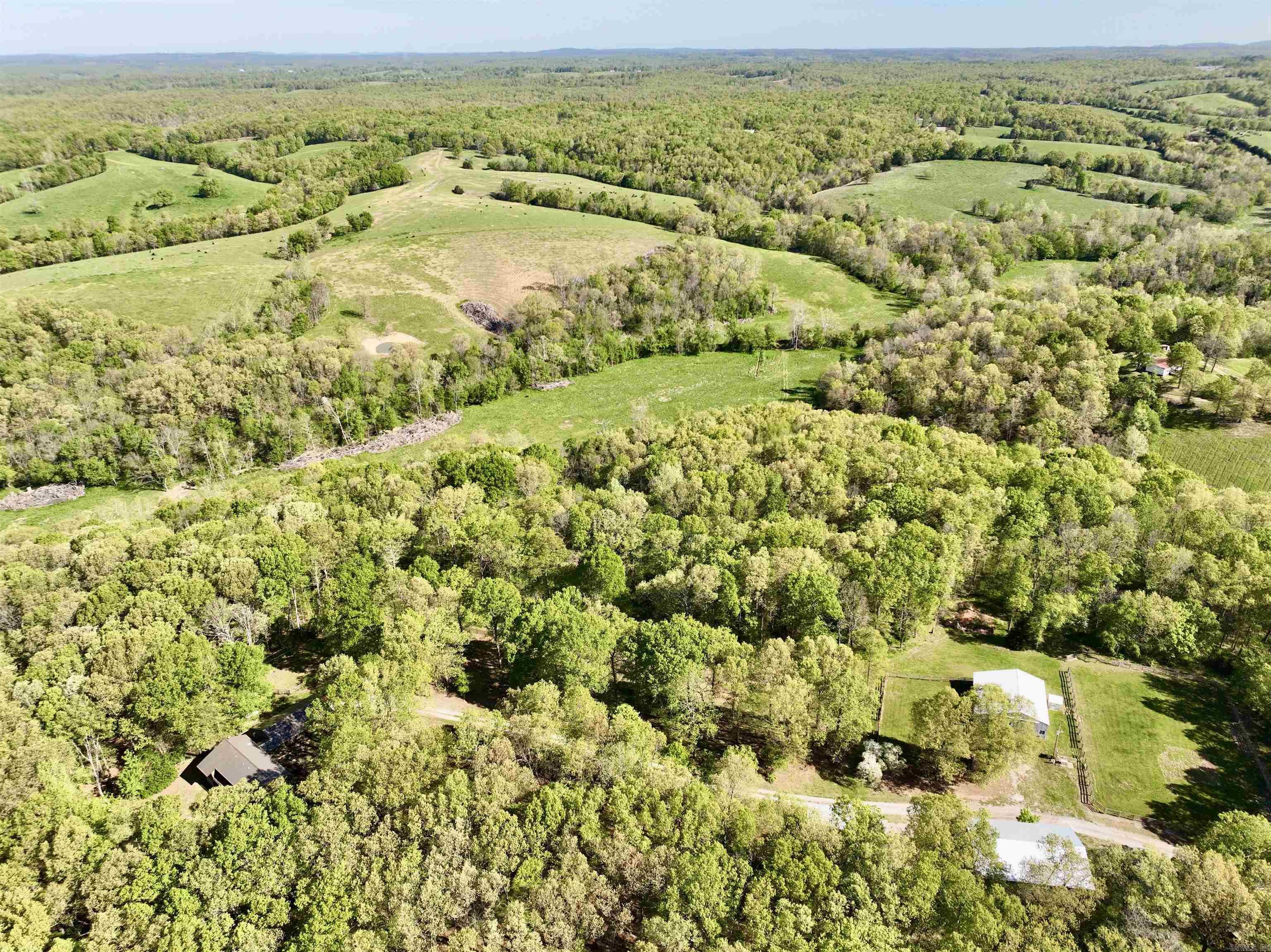 Nestled in the picturesque heart of the Ozarks, Stony Creek Horse and Cattle Ranch beckons with its idyllic charm and convenient location just 10 minutes from Huntsville, north of 412. A mere 40 to 45-minute drive takes you to the vibrant communities of Springdale and Fayetteville, while the serene shores of Beaver Lake and the quaint allure of Eureka Springs are within 30 minutes' reach. The centerpiece of this sprawling estate is a spacious custom-built home boasting three bedrooms and two and a half baths. It is thoughtfully designed and features updated heating and air units and a propane-powered generator for added comfort and security. With numerous upgrades and cozy amenities like a fireplace insert and wood furnace, it offers a welcoming retreat for every season. The open floor plan seamlessly blends functionality with style, complemented by an office and a roomy master bedroom with a luxurious bath. Outside, the property unfolds into a haven for equestrian enthusiasts and nature lovers alike. Fenced and cross-fenced pastures, along with holding and working pens, provide ample space for livestock management.