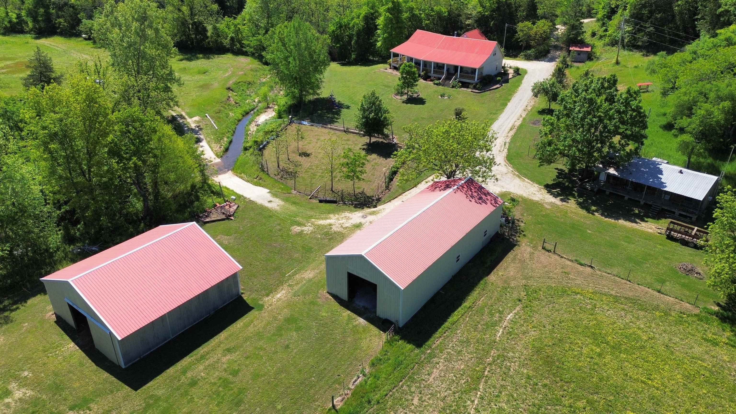 This is a prime 220 +/- acre hunting and recreational ranch with a true self-sufficient homestead, featuring a spring creek–irrigated garden that is surrounded by a fruit orchard of apples, peaches, blackberries, and muscadines. Approximately 5,000 feet of South Indian Creek runs through the middle of the property.  The home features 4 bedrooms—3 on the main level and 1 upstairs as a bonus room. There’s a large country kitchen and a great room centered around a massive stone, wood-burning fireplace. There is also a guest cabin, located within walking distance of the main house, that comfortably sleeps six. One of the best features of the home is the wrap-around front porch overlooking the creeks and garden, where you can often see wildlife right from your seat. This is truly a turkey hunter’s paradise. There are two large metal buildings—one is a shop with a big electric overhead door, and the other has 4 horse stalls with overhead hay storage.  The property includes numerous small food plots and about 60 acres of creek bottoms that can be used for hay or larger food plots. With 2 year-round creeks and 2 year-round springs, there’s all the water you could ask for— only $950,000.