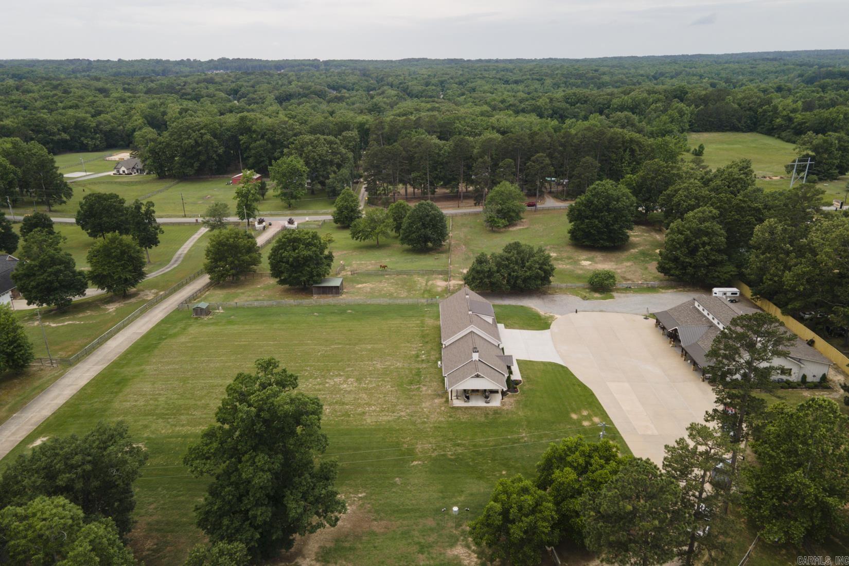 An outdoorsy dream 2 house estate tucked away just outside of West Little Rock. 4 bedroom, 3.5 bathroom beautifully designed barndominium on 13 acres with matching modern guest home. The main property features both a master suite and guest suite on the first level, open living space, formal dining, office/bonus room, creative flow space and oodles of smart storage. Upstairs two generously sized bedrooms both with walk-in closets share a third full bathroom. Front acreage is cleared and fenced for hobby farming or equestrian use, great shade trees throughout, and further past the homes lies a stocked pond with lighted pavilion island which make summer evenings dreamy and full of fun! The 1800 sq. ft. shop with 25 ft. bays can house all your favorite outdoor equipment. Guest home has living area, master suite, full service kitchen, and upstairs loft which can fit 3 twin beds! Attention given to all the details make this a diamond listing, truly one of a kind. Agents see remarks.