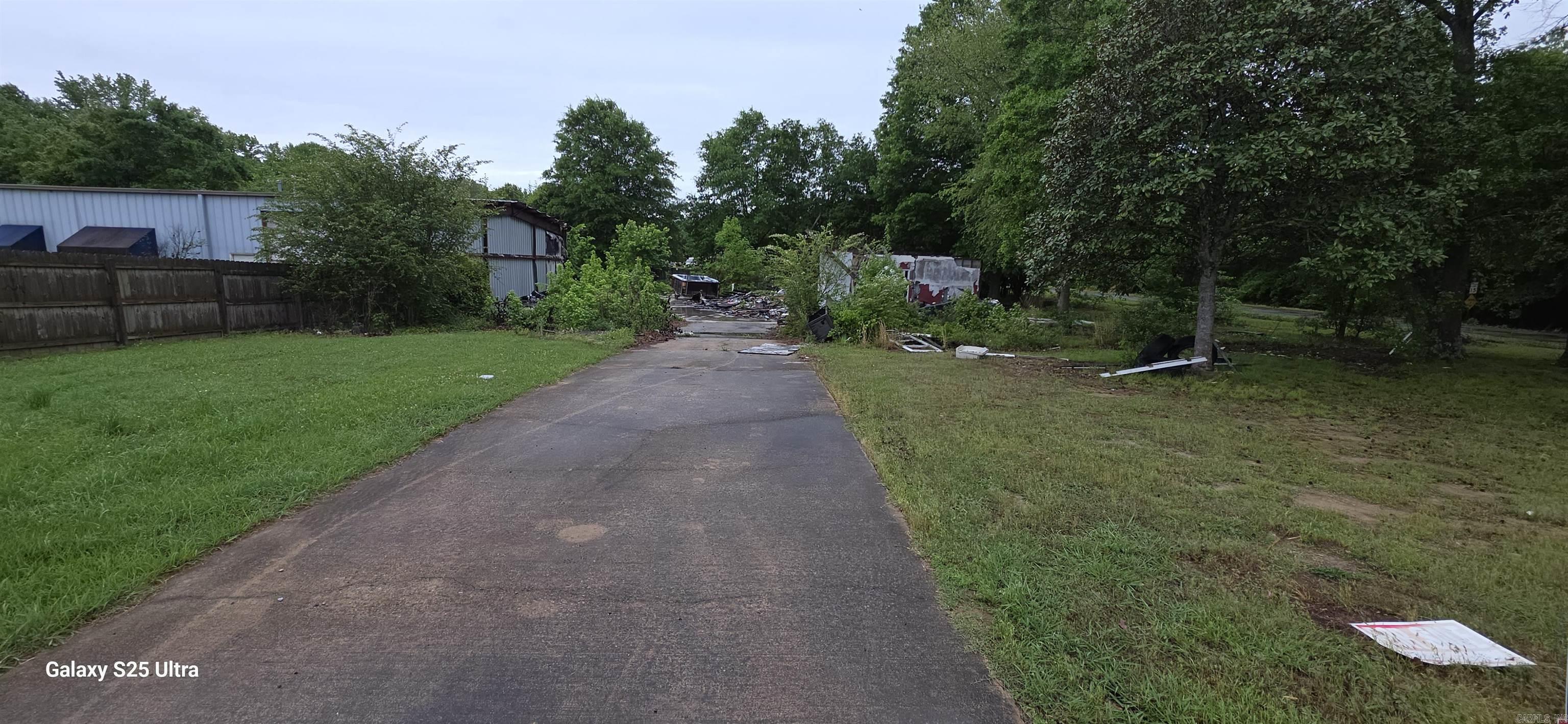 Corner lot with mature hardwoods. Prior structure was a shop with apartment that burned. Current owner is trying to get the debris cleared, however property be sold as is. Remaining side if the building is occupied and owned by a different party. Good investment potential, subdivisions being developed directly across the street.