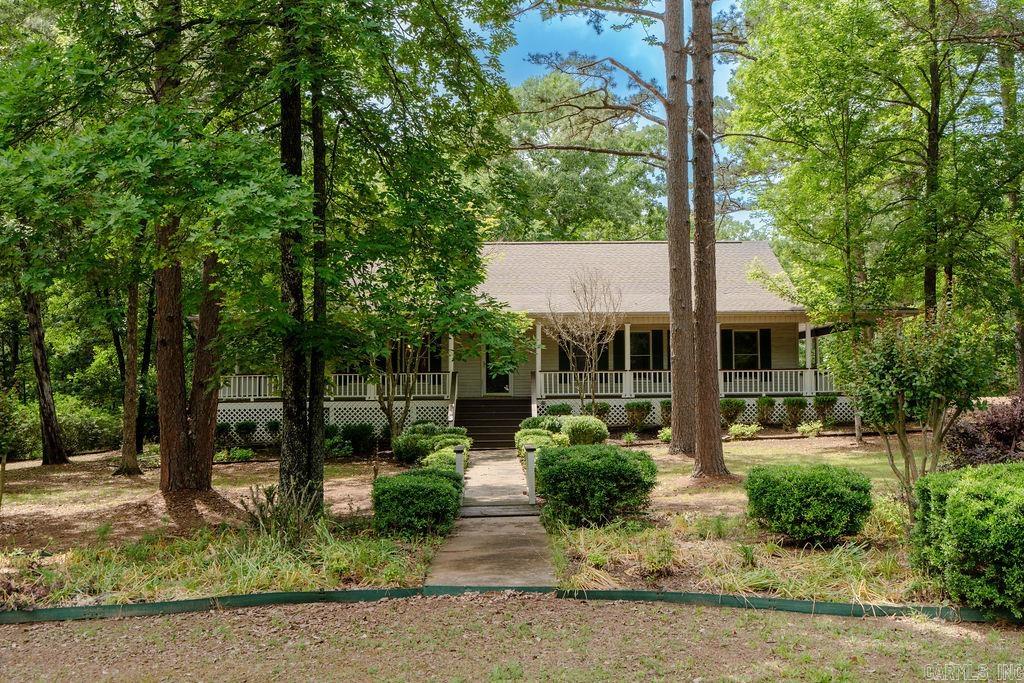 This spacious country-style home sits on a beautiful 1.8-acre corner tract and welcomes you with a large wraparound porch perfect for relaxing and enjoying the peaceful setting. The 1,872 sq ft main level offers a split floor plan with a private primary suite separate from the guest bedroom. The primary ensuite features a new tiled walk-in shower, double vanity, and oversized walk-in closet. Fresh interior paint and new LVP flooring throughout the main level create a clean and updated feel, while the living room offers a cozy gas log fireplace. The kitchen is built for entertaining with a large island featuring a built-in gas range, plus a wet bar with ice maker. The dining room includes a full wall of built-ins for added storage. The finished basement adds a large game room or second living area, an additional bedroom, spacious safe room ideal for crafts or a workshop, plus fresh paint and new LVP in the living areas. Enjoy the peaceful wooded backdrop from the spacious deck. Attached 2-car garage plus an impressive heated/cooled 40x50 shop with shelving, 50-amp breaker, four 30-amp breakers, heated/cooled bonus room, chair lift, and motorized platform lift. Take a look!