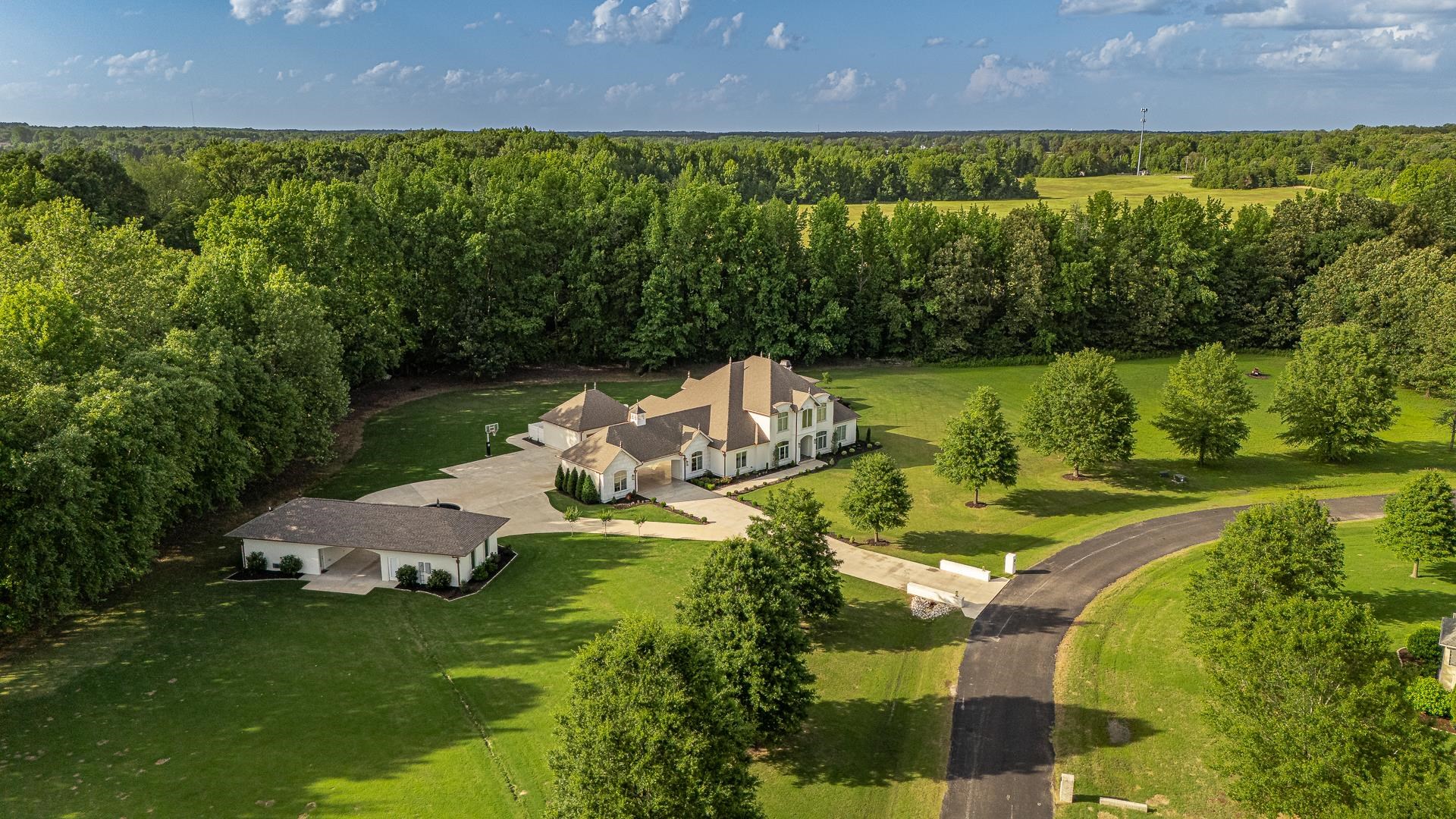 This stunning estate blends luxury, comfort, and elevated design into one unforgettable address. The main-level Owners’ Retreat is a true sanctuary with marble floors, a spa-like steam shower, slipper soaking tub, double vanities, private water closet, and two custom closets—one a built-in safe room. A separate main-floor guest suite adds comfort and privacy. At the heart of the home, the chef’s kitchen stuns with a grand island, premium finishes, and seamless flow to the great room, office nook, wet bar, and guest half bath. The laundry room even includes its own exterior door for added convenience. Upstairs offers three additional bedrooms, two full baths, a second office nook, and abundant storage. Outside is where this home truly shines—relax by the saltwater pool, rinse off in the outdoor shower, and cook in a fully-equipped outdoor kitchen with built-in grill, prep space, and bar seating. The detached pool house brings year-round entertaining to life with a wood-burning fireplace, full bath, and wet bar, while a separate studio apartment with kitchenette and full bath offers space for guests or creative escape. With five garage bays and flawless attention to detail throughout