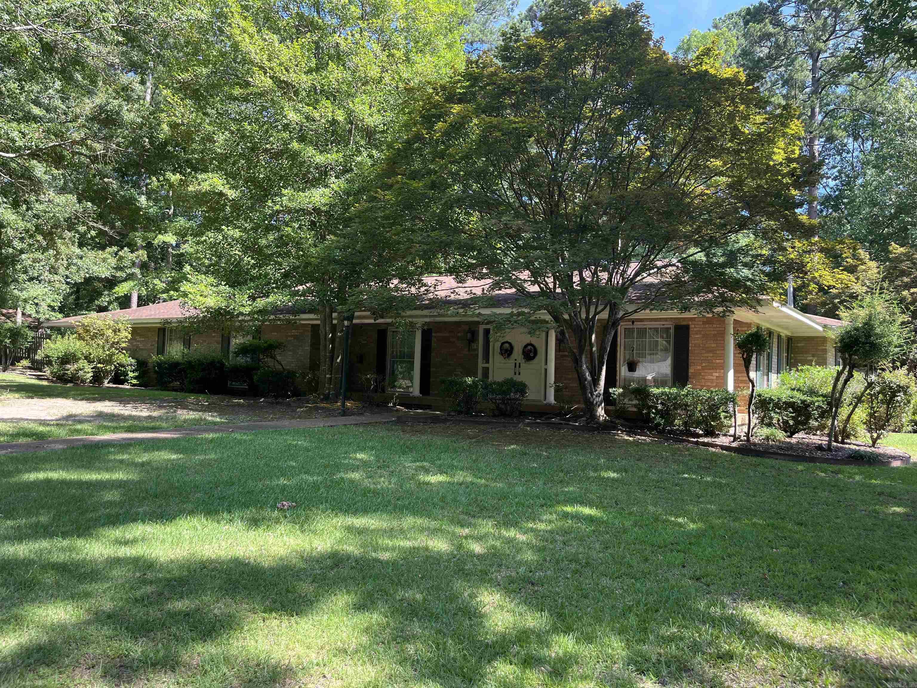 This home welcomes you to a lush front yard and exquisite curb appeal. Located in the heart of Magnolia and just minutes from Southern Arkansas University. To the left of the entry is a formal living room and to the right a formal dining room anchored by an elegant chandelier. Designed and built for entertaining the home features a massive den with fireplace that provides a vocal point. Both stylish and practical, the kitchen is equipped with undercabinet lighting, abundance of cabinets, refrigerator, double oven, cooktop, trash compactor, and dishwasher. The laundry room with sink is adjacent to the kitchen. Don't miss the beautiful office with wood cabinets and fireplace that adds even more character and charm. The spacious master bedroom has an ensuite bath with double sinks, shower and walk-in tub. There are two additional bedrooms, hall bath and half bath in hallway for guests. When driving into the carport you are welcomed with a black wrought iron gate leading to the patio. Other amenities include additional parking, sprinkler system, guest house  with kitchen and bath, and fully fenced yard. For your private showing give Linda Anders at Jan's Realty a call 870-904-0147.
