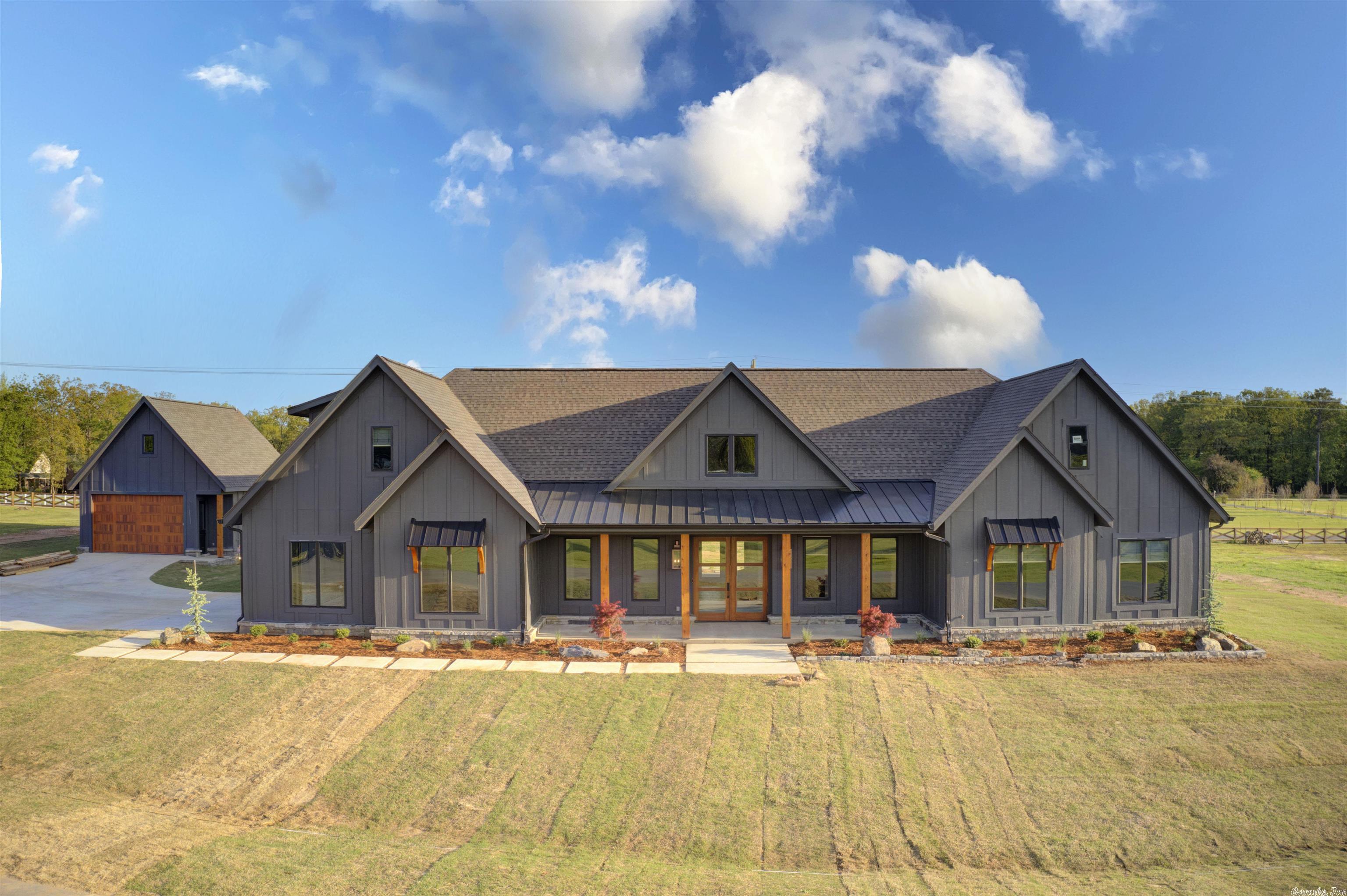Modern meets Rustic w this Custom Builder's Personal home on 1.3 Acre Lot in Gated Community. Foyer opens into a stunning open kitchen & dining space framed w reclaimed hand-hewed barn timbers. Chef's kitchen features island w breakfast bar, 6 burner gas range, quartz countertops, extensive cabinetry, & walk-in Butler's Pantry w coffee bar. Grand living room showcases cathedral ceiling w mechanically antiquated poplar wood trusses, natural Arkansas stone fireplace w gas starter, & oversized chandeliers. Primary suite is private & includes cathedral ceiling, custom tile shower, double vanities w gorgeous gold mirrors, & large walk-in closet. 2 bonus rooms, one on main level & one upstairs w a bathroom, makes this property great for a large family. Modern & sleek office w built-in desk. Huge laundry room w sink & ample cabinet space. Mudroom area w enclosed lockers. Beautiful covered back porch w outdoor kitchen & fireplace overlooks flat backyard & veranda for hot tub (doesnt convey). 3 car garage & separate 2 car shop w bathroom & space above that could be finished out &made into an apartment. Energy Efficient HVAC & HW heater, hot/cold valve outside, & landscape lighting.