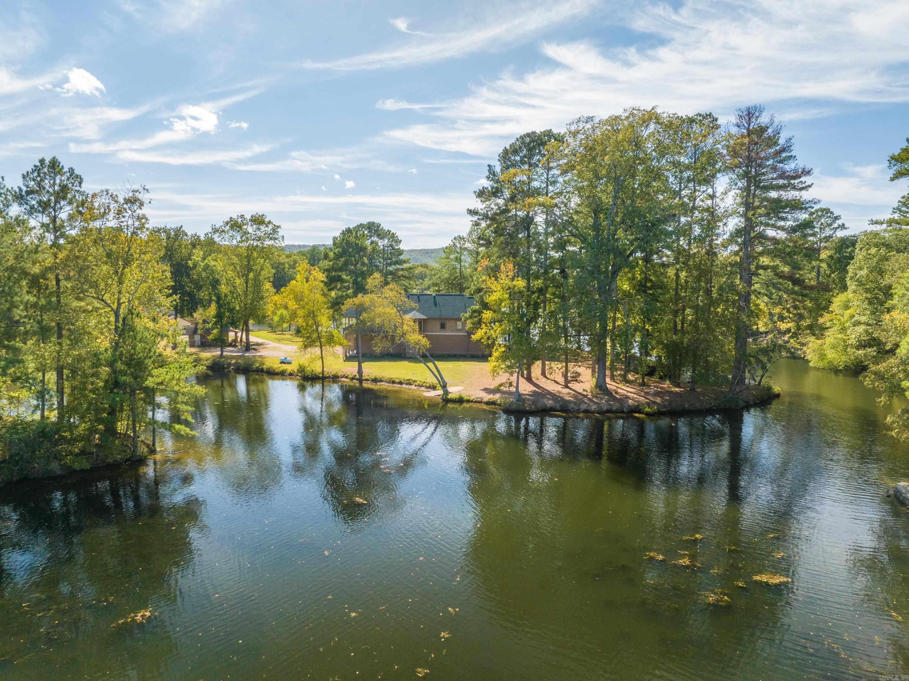 Welcome to your private oasis on a 2.8-acre peninsula, boasting an impressive 1700 feet of pristine lake frontage! This exquisite property offers the perfect blend of rustic charm and modern luxury.  Nestled amidst nature's beauty, the primary residence is a custom-built 3-bedroom, 2-bathroom masterpiece. Crafted with a keen eye for detail, it exudes rustic character. The spacious living area features a stone fireplace and panoramic windows that frame stunning lake views. The chef's kitchen is well-appointed with top-of-the-line appliances and a large island.  Two 1-bedroom, 1-bathroom cabins offer guests a cozy retreat. Perfectly situated for privacy, they provide an ideal spot for extended family or rental income potential.  Outside, enjoy endless activities from your own backyard. Fish, swim, or kayak from your private dock. Explore the surrounding woods, or simply unwind on the sprawling deck overlooking the serene waters. The enchanting sunsets will leave you in awe.  This unique property combines the serenity of lake living or the potential for instant cash-flow through an already successful and profitable VRBO business! VRBO Financials available on request.