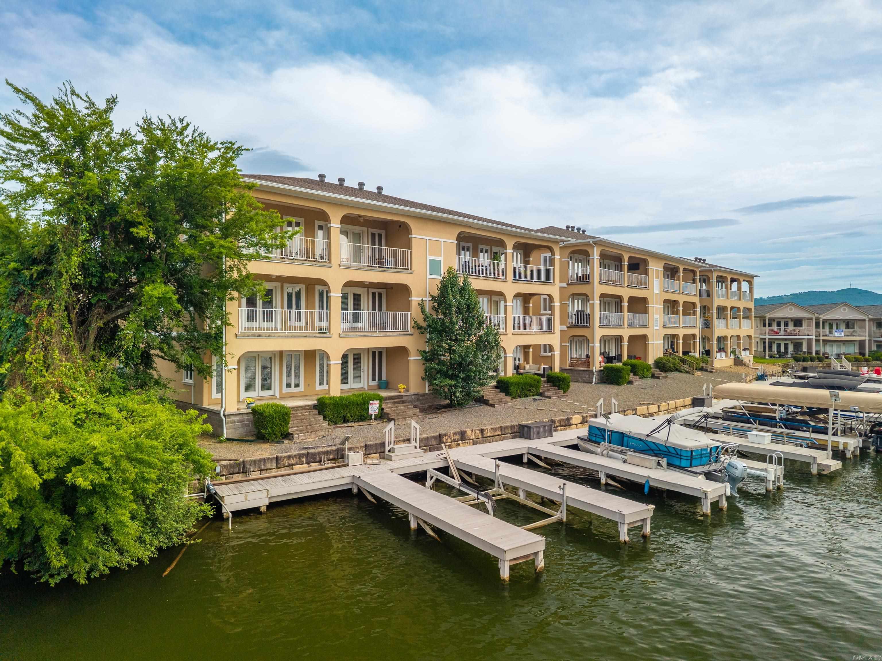 Experience lakefront living at its finest in this spacious 2,455-square-foot condo offering breathtaking water views and exceptional amenities. Located within a gated community, this 3-bedroom, 3.5-bath residence includes a private boat slip, community swimming pool, and expansive upper and lower decks perfect for relaxing or entertaining while enjoying the lake scenery. The versatile floor plan features a welcoming main level with a spacious living area, wet bar, bedroom, full bath, and half bath ideal for guests or additional living space. Upstairs, the open-concept design showcases a bright and airy living room, dining area, and kitchen, all positioned to capture stunning lake views. Two additional bedrooms and two full baths provide comfortable accommodations for family and guests. Whether you're looking for a full-time residence, vacation getaway, or investment opportunity, this lakefront condo offers the perfect combination of comfort, convenience, and waterfront lifestyle.