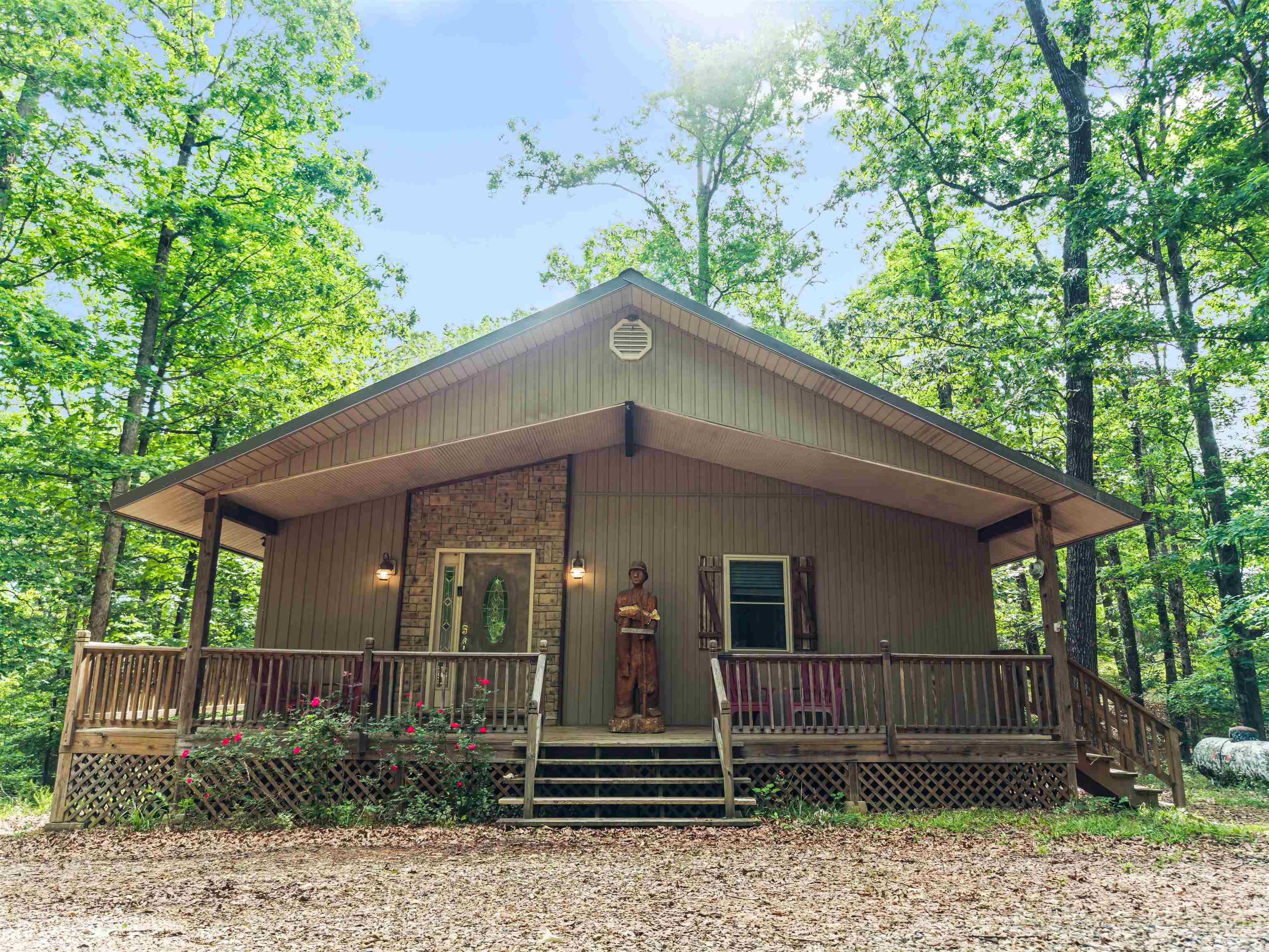 Rare opportunity just 1 mile from Twin Creek boat ramp on Lake Ouachita — one of the clearest lakes in the nation. Nestled on 1.5 private wooded acres, this fully furnished, turnkey two-story cabin is unlike anything currently on the market. The main level features a stunning great room with soaring knotty pine vaulted ceilings, exposed log beam, hardwood floors, fireplace, and a wall of French doors opening to a massive covered deck with outdoor dining and fire pit seating — all surrounded by towering hardwoods. The lower level sets this property apart — a rec room with second fireplace and kitchenette, private bedroom suite, woodland-themed bunk room sleeping 8, and full bath with double vanities. A large detached garage with power is perfect for boats, ATVs, and lake toys. Fully fenced with gated entry. Currently operating as a successful short-term rental and income-producing from day one. With Lake Ouachita's world-class fishing, boating, and year-round recreation just around the corner, demand in this area is exceptionally strong. Properties like this rarely hit the market.