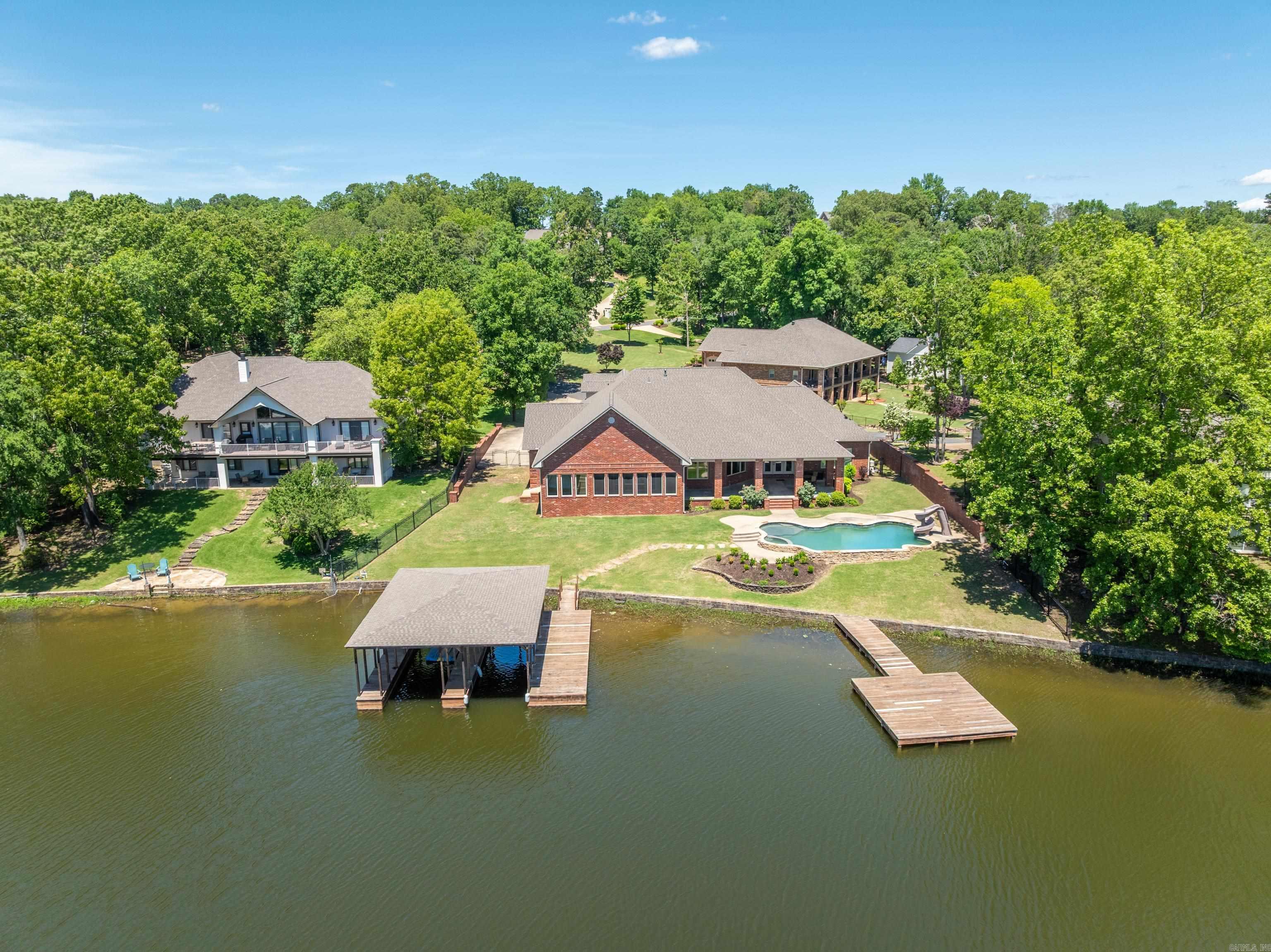 Custom Lake House on Lake Hamilton - A Waterfront Dream Home Discover an extraordinary custom-built lake house, perfectlypositioned on the serene shores of Lake Hamilton. This remarkable property spans 0.66 acres with an impressive 154 feet of lakefrontage, offering unparalleled views and direct access to the water. Spacious Living: With over 4,600 sq ft of living space, this homefeatures 5 bedrooms and 4 bathrooms, providing ample room for family and guests. Gourmet Kitchen: The large gourmet kitchen is achef’s dream, boasting top-of-the-line appliances, custom cabinetry, and expansive countertops—ideal for preparing meals andentertaining. Multiple Living Areas: Designed for comfort and versatility, the home includes multiple living areas, perfect for relaxing orhosting gatherings. Two cozy fireplaces add warmth and charm to the main living spaces. Primary Ensuite: The large primary ensuite isa true retreat, offering a luxurious bathroom and generous closet space. Outdoor Entertaining: The outdoor areas are an entertainer'sparadise, featuring a spacious screened-in porch, ample decking, and various spots to enjoy the lake views. Dive into the in-groundGunnite pool, complete with a