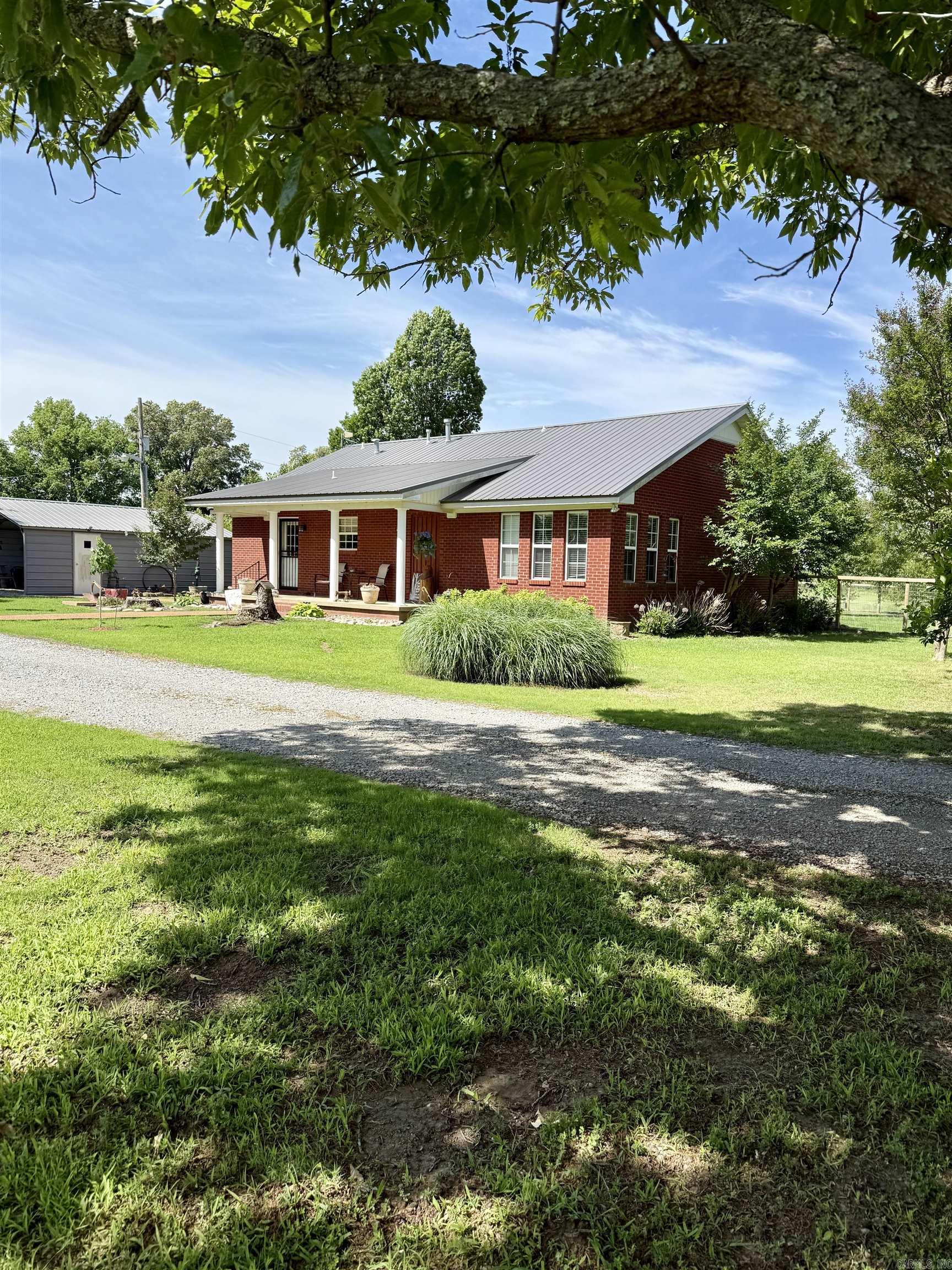 Welcome to your own slice of the Arkansas Delta!   Nestled on 11.3 acres just south of Marvell, AR in a small community called Trenton, this beautifully maintained 2 bedroom, 2.5 bathroom home offers the perfect blend if comfort, functionality, and country living.   Step inside to an inviting open- concept layout featuring vaulted ceilings with exposed wood beams, warm wood accents, and abundant natural light. The spacious kitchen is the heart of the home, complete with a large island, ample cabinetry, and modern appliances- ideal for entertaining or everyday living. The adjoining living room area provides a cozy yet open space to relax, highlighted by large windows overlooking the property.   Enjoy peaceful mornings and evening on the covered porch, taking in scenic views and quiet surroundings. Outdoors the property truly shines with a stocked pond, open acreage, and plenty of room for livestock, recreation, or simply enjoying the outdoors.   A large metal shop offers excellent storage for equipment vehicles or hobbies, making this property as practical as it is charming.