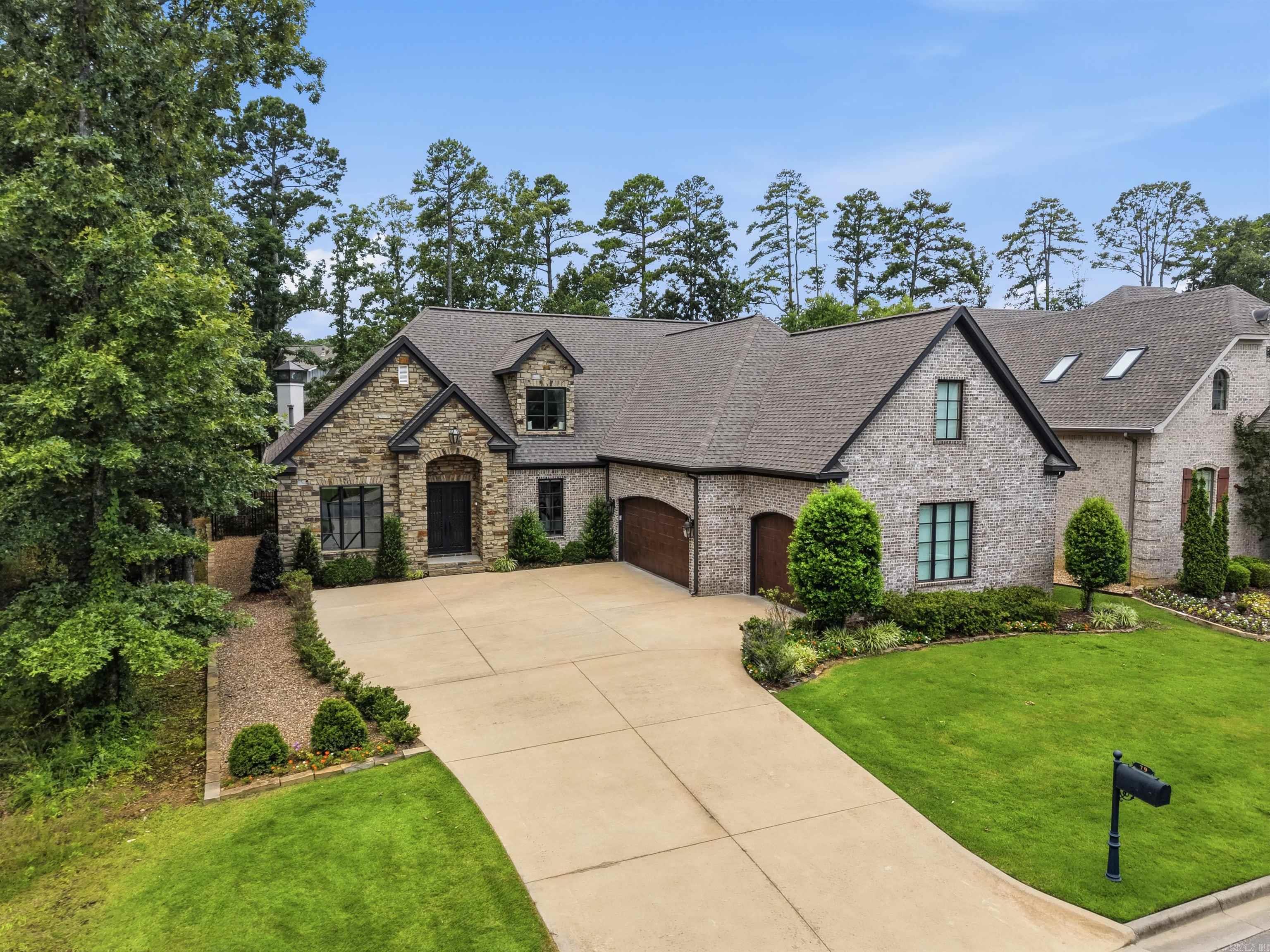 Welcome to 79 Hallen Court, a beautifully appointed home in the sought-after Hallen Court neighborhood of Chenal Valley. Featuring exceptional curb appeal with a timeless brick and Arkansas natural stone exterior, maintenance-free garage doors, and a classic gas lantern, this home is just steps from the Bear Den Golf Course & Chenal Valley Country Club. Completed in 2018, it showcases quality craftsmanship, Andersen windows with abundant natural light, and a thoughtfully designed floor plan. The gourmet kitchen features quartz countertops, custom cabinetry, a large island, 45" GE Café gas range with double ovens, built-in refrigerator & freezer, ice machine, prep sink & walk-in pantry. The main level includes a private office, primary suite with spa bath and dual closets, a guest suite with en-suite bath, laundry room & mudroom. Upstairs offers a game room, 2 bedrooms w/ walk-in closets, hall bath, exercise room & walk-in attic storage. Enjoy year-round outdoor living with a covered patio, wood-burning fireplace, turf backyard & iron fencing. Additional features include a three-car garage, new hardwood floors and carpet, new custom built-ins, and updated lighting throughout.