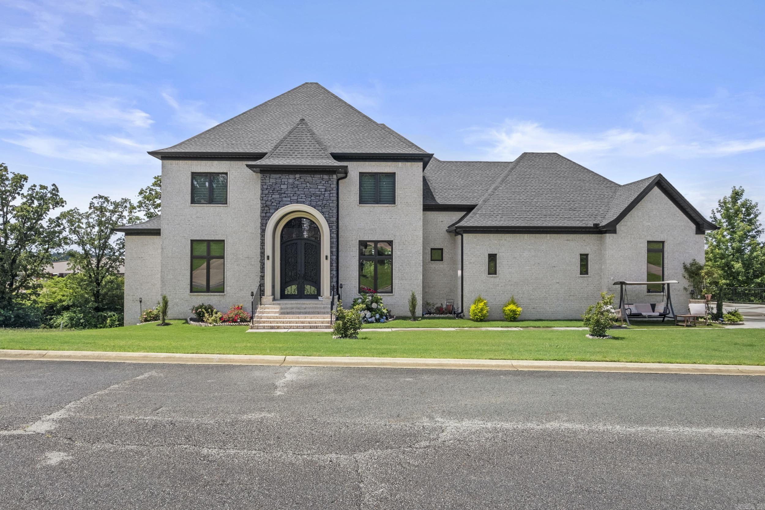 Say hello to your dream home at 18 River Ridge Rd in Searcy, AR, located in the desirable River Oaks Subdivision. This luxury home sits on a 0.54± acre lot and offers 7,465 sq ft of well-designed living space spread across three levels. The main floor features an open-concept living, dining, & kitchen area with an abundance of natural light, a gas log fireplace with tile surround, & an eat-in kitchen complete with two granite-topped islands, a walk-in pantry, & access to a spacious balcony with stunning views. The primary suite is a peaceful retreat with large, bay windows, private balcony access, a walk-in closet, & a tiled shower in the en suite bath. Main level also includes a large guest bedroom with a private en suite, separate half bath, laundry room, office & a three-car garage with golf cart storage. Upstairs, you’ll find a large open landing, two bedrooms with private en suites, two additional bedrooms connected by a Jack-and-Jill bathroom, & access to a balcony with breathtaking views. The basement offers even more living space with a second kitchen, living area, full bath, additional laundry room, & 2 storage/flex rooms. This home truly has it all! Call today for a tour!