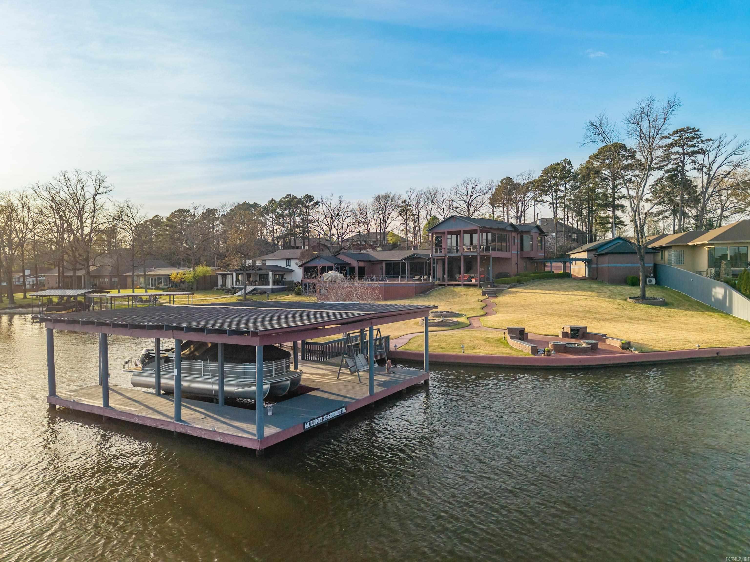Stunning home on 257' of prime Lake Hamilton frontage with seawall and two covered boat docks. This 6700 square foot estate offers 5 bedrooms, 6.5 bathrooms, and exceptional indoor-outdoor living. Enjoy the saltwater pool, expansive entertaining spaces, home theatre, wine cellar, and breathtaking views from nearly every room! Thoughtfully designed with luxury finishes, multiple living areas, and beautifully landscaped grounds-perfect for entertaining or lakeside relaxing.
