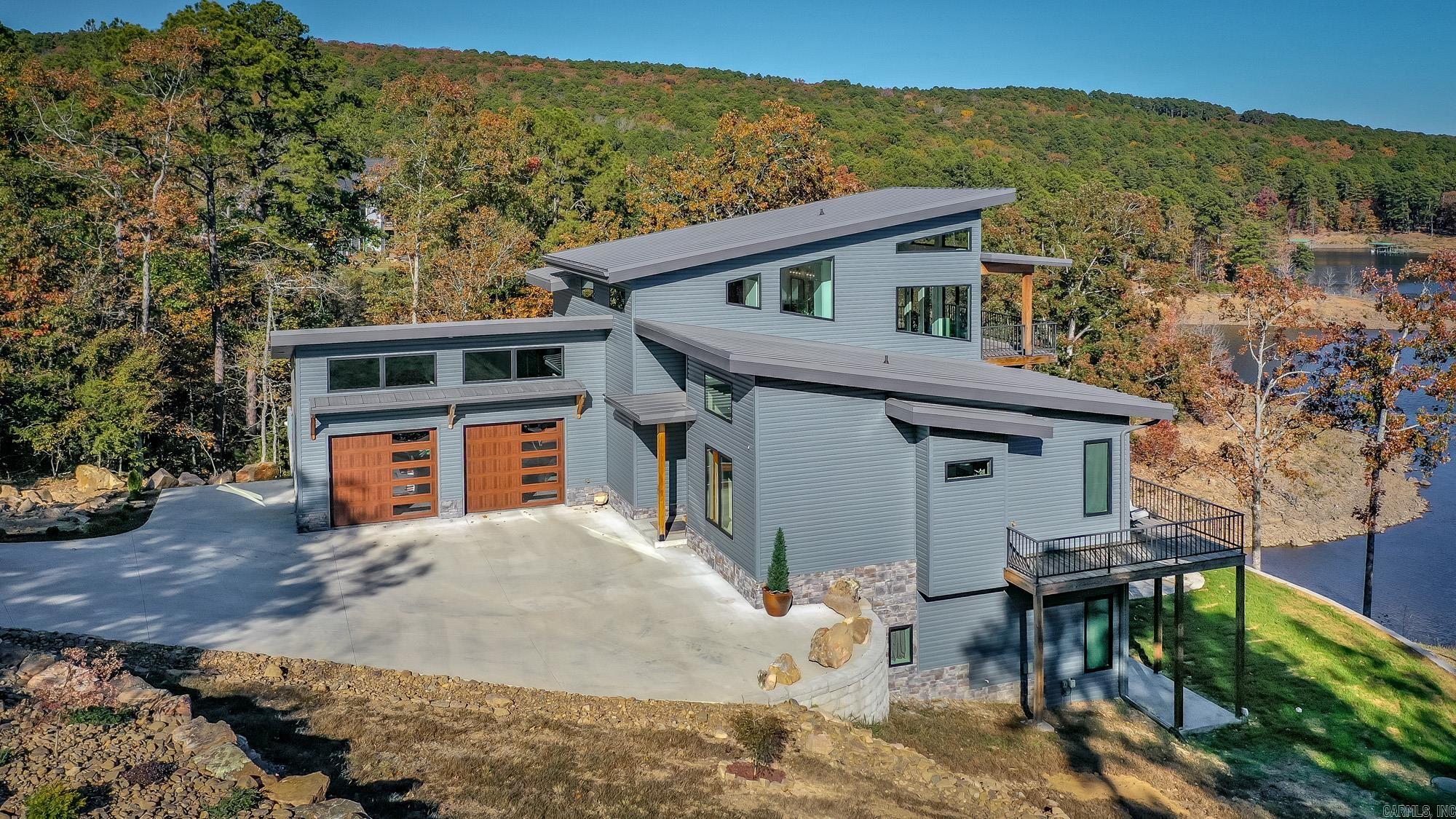 Breathtaking Modern Lakefront Retreat with Boat Slip Welcome to your dream lakefront oasis on the shimmering shores of Greers Ferry Lake! Nestled on nearly 2 acres with a rare sandy beach area and boasting direct water access with the white line in the water, this exceptional modern home combines luxury living with spectacular natural beauty. Step inside to a bright, open-concept living space, where a dramatic wall of windows frames panoramic views of the lake & fills the home with natural light. Entertain with ease on the expansive main-level deck or unwind in the lower patio area complete with a relaxing jacuzzi, which conveys with the property. The private deck off the primary suite is perfect for peaceful mornings sipping coffee as you watch the sun rise over the water. The chef’s kitchen is a showstopper with custom white oak cabinetry, gorgeous granite countertops, & a generous butler’s pantry, ideal for hosting family & friends. The thoughtfully designed interior seamlessly blends modern aesthetics with warm, inviting finishes. Impress your guests with unmatched indoor-outdoor living & end the day with toes in the sand at your own beach. A deeded boat slip & lift will convey