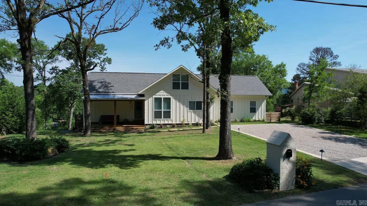 Tucked into a quiet Lake Hamilton cove with 110 feet of deeded waterfront, this 2020 Craftsman-style home delivers lake and mountain views, a private covered two-slip boat dock, and an open-concept layout with vaulted ceilings — all on a 1/2-acre lot. Dual primary suites with en-suite baths. Third bedroom with easy access to a full hall bath. Every bedroom opens directly to the back deck. Dedicated laundry room in the bedroom wing. Bonus loft above the main living area adds flexible space. Stone countertops, upgraded appliances, and a built-in beverage center. Graveled fire pit terrace between the deck and shoreline, with steps to the private covered dock. Two slips accommodate boats and swim access is available directly from the dock. Proven short-term rental with a 4.98-star rating across 42 Airbnb reviews; STR permit transferable. Select furnishings available for a turn-key transition.