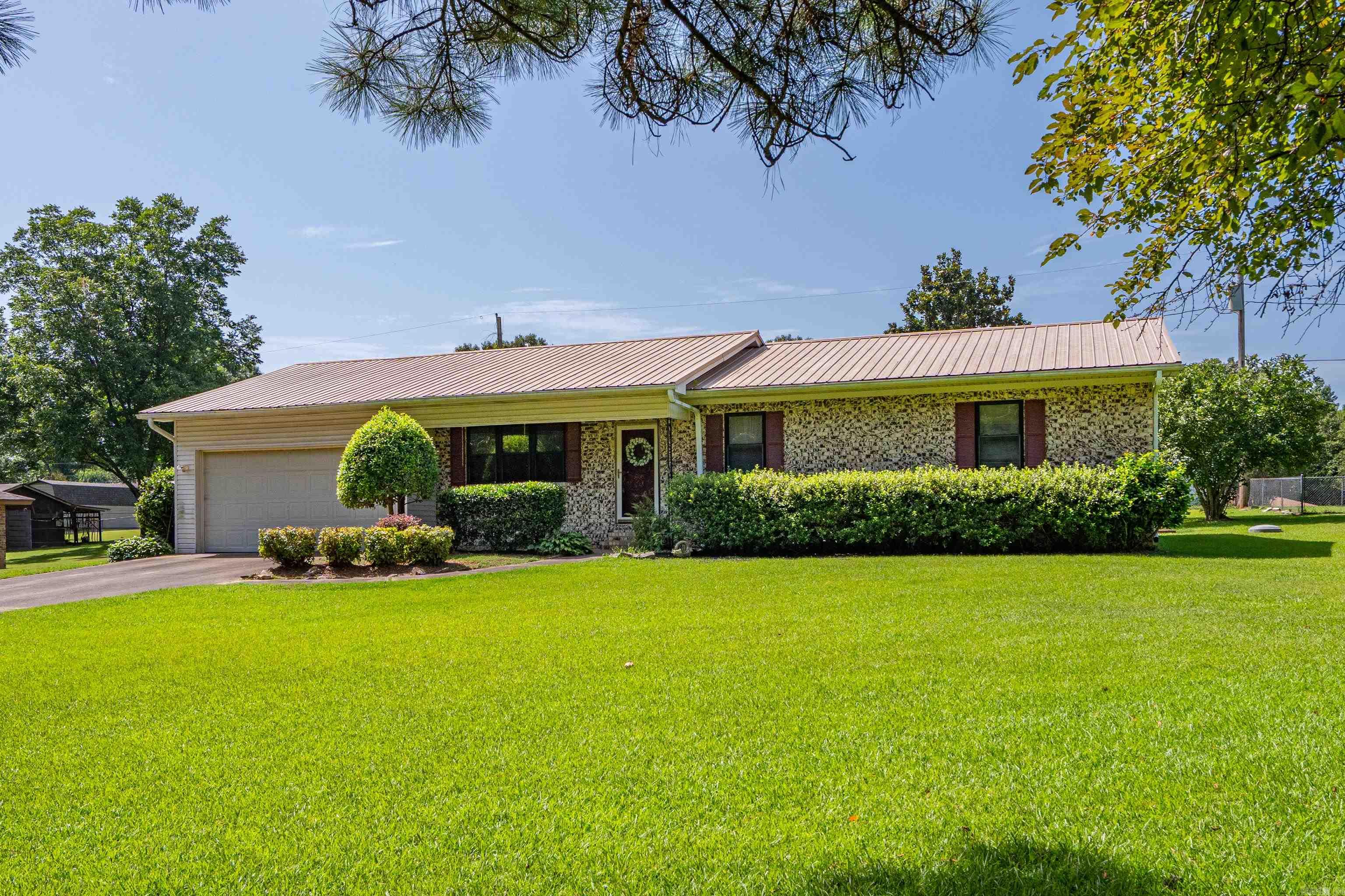Don't miss this one!!! Solid, well-maintained brick home in a highly desirable neighborhood where homes rarely become available! Located just outside the city limits on a quiet dead-end road, this 3-bedroom, 2-bath home features a spacious family room with walls of windows overlooking the beautifully landscaped backyard and a cozy gas fireplace. Enjoy mature rose bushes, crape myrtles, hydrangeas, and Rose of Sharon, plus a wood deck perfect for relaxing. Additional features include a large utility room, two-car garage, portable generator hookup, storage building, and an extra metal carport. A rare opportunity in a location buyers love!