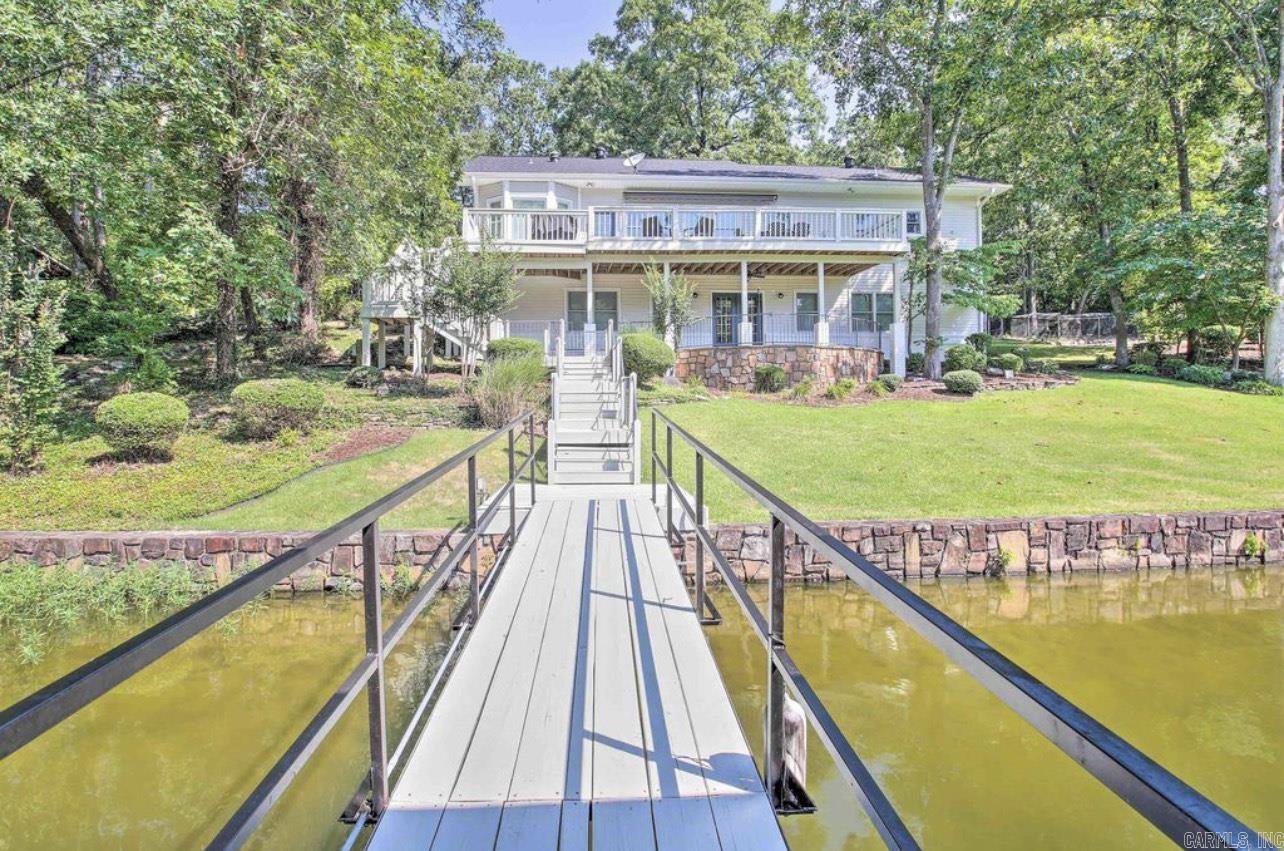Beautiful, breathtaking property located on the water’s edge of Lake Hamilton!  This stunning home leaves nothing to be desired. Featuring FIVE bedrooms and THREE full bathrooms, this home has plenty of room. The large living area and kitchen provide plenty of space for hosting guests! Stunning new designs throughout the home inside and out make it a sought after property on the lake! Tired from a day on the lake? Your master suite shower has a steam option turning it into a relaxing sauna! The whole home generator is an added bonus for peace of mind. Downstairs you will find an open area living space, along with a wet bar, one bedroom, and one full bathroom. Step out onto your spacious upstairs deck for a relaxing evening by the lake. Enjoy the huge backyard by sitting at your fire pit just feet from your 175 feet of lake frontage! Enjoy your own covered boat dock for easy access to everything that Lake Hamilton has to offer. A separate 975 sqft garage offers plenty of space for parking or storage and also has a shop area located inside. This property also boasts an outstanding investment opportunity in the booming short-term rental market. A highly profitable property for sale!