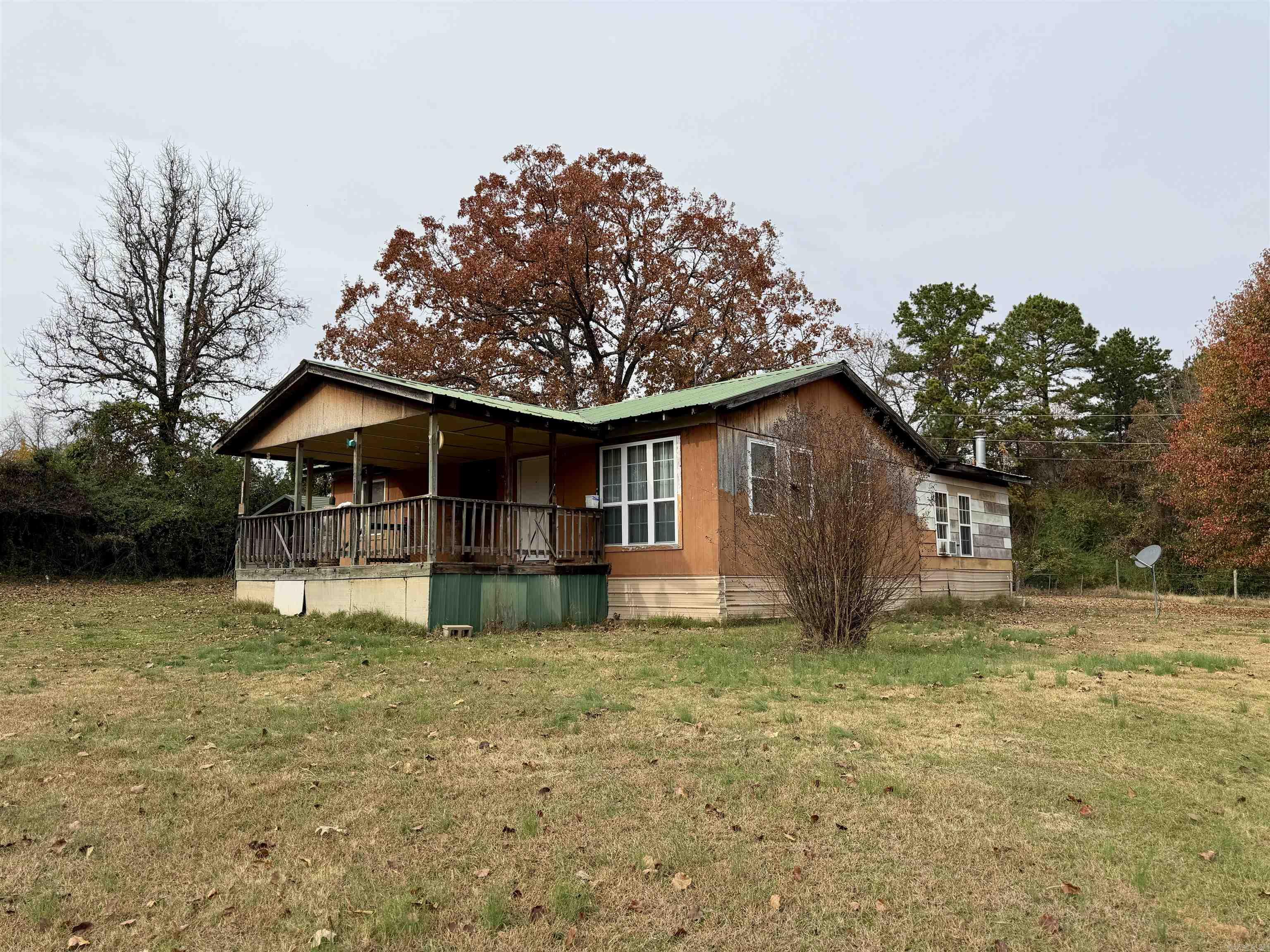 Tucked away on 4.5 peaceful acres with a stocked fishing pond and plenty of privacy, this unique country property offers the feel of a small family compound waiting to be brought fully to life. The main home features 3 bedrooms and 1 bath with a split floor plan, an inviting oversized front porch, a metal roof, and HVAC installed in 2015. Just steps away sits the charming 1-bedroom tiny home, designed with efficient living in mind and offering a cozy living and kitchen combination area, full bath, laundry space, and comfortable front and rear porches—the back porch offering a tranquil view across the pond.  The tiny home includes a modern mini-split heat and air system, though appliances are not included. The property also offers several useful outbuildings, including a double carport, barn, and chicken coop, ideal for hobby farming, storage, or a workshop. With few neighbors and room to spread out, this property provides the quiet of country living with endless potential. To be sold as-is, as the home needs completion, and should qualify for an in-house loan or possibly FHA rehab financing.