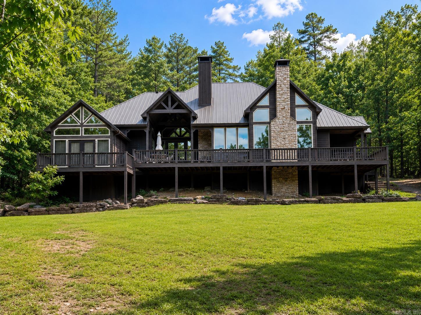 Modern comfort meets classic cabin charm in this beautifully designed 3BR/3BA home nestled on 1.25 wooded acres in the gated community of Primrose Creek. Surrounded by mature hardwoods, this peaceful retreat offers a full-length deck with stunning views of Libby’s Bluff and seasonal views of the Little Red River. Outdoor living is a highlight with a spacious deck and outdoor fireplace, perfect for relaxing or entertaining. Inside, you’ll find beautiful post-and-beam construction, vaulted wood ceilings, wood plank flooring, a stone fireplace, and an open kitchen with granite countertops, large island, and dining area. The floor plan includes separate in-law quarters as part of the 3BR/3BA layout, offering flexibility for guests, extended family, or a private retreat. Enjoy Primrose Creek amenities including pool, covered pavilion, community boat dock, private launch area on the Little Red River, picnic area, firepits, and fishing pond. Minutes from Greers Ferry Lake, restaurants, and shopping. Property is being sold furnished! Schedule your showing today!