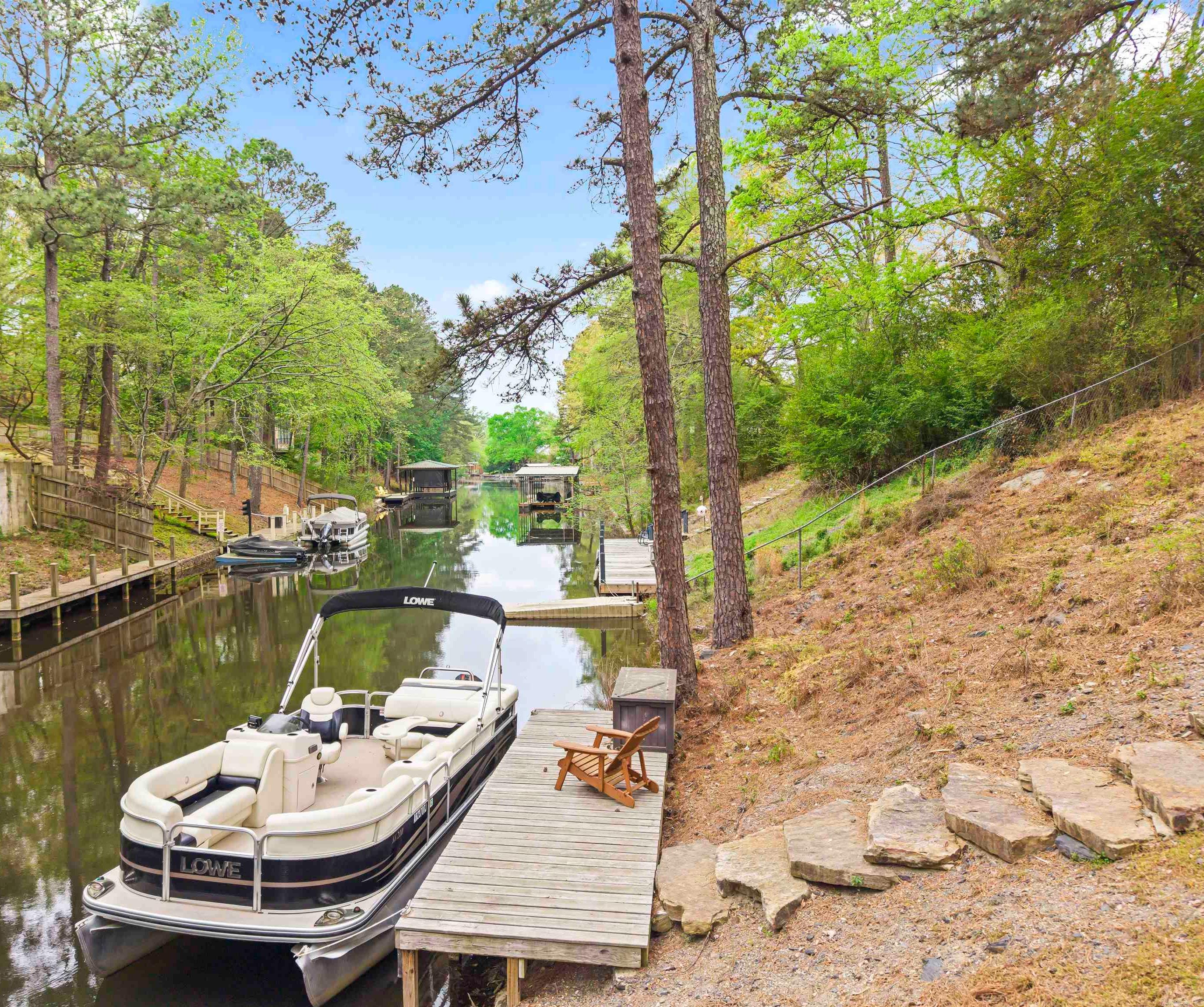 Lake Hamilton Waterfront | 4-Car Garage | Guest Apartment | One Owner Custom Home Rare opportunity to own a beautifully updated one-owner custom waterfront home on Lake Hamilton! Appraiser-measured 1,908± sq ft includes a 3BR/2BA main home featuring engineered hardwood floors, abundant storage, an updated kitchen, and a cozy living area with a stone wood-burning fireplace. The main level offers comfortable living and an easy flow for everyday life and entertaining. Outdoor living is exceptional with two levels of decks, a firepit area, stone steps leading to the private boat dock, and a black metal dog run ideal for pets. Storage and parking are a standout feature with generous storage inside the home, an attached 2-car garage, plus oversized detached garage  w/1/2 bathroom - room for vehicles, lake toys, or hobbies Above the detached garage is a private heated/cooled studio guest apartment with its own entrance, full kitchen, full bath—ideal for guests, multigenerational living, rental or a home office. Conveniently located near shopping, dining, and medical facilities, this property offers a rare combination of waterfront lifestyle and ADU Seller is a licensed real estate agent.