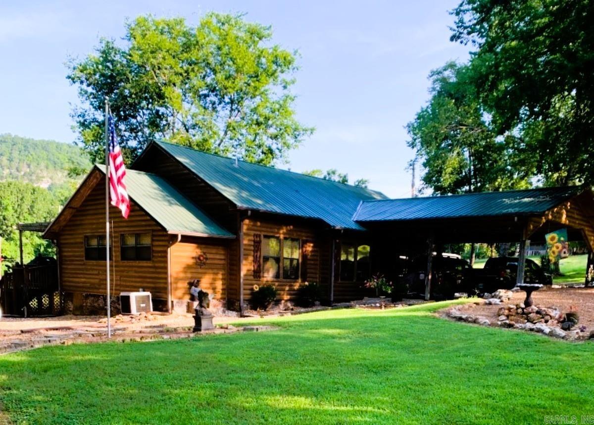 Lodge-style charm near the White River!  This 2 bed, 2 bath home offers 1,492 sq ft with an office that could be a 3rd bedroom, spacious kitchen, two dining areas, cozy living room, and a den with a wall of windows. Enjoy outdoor living with a screened-in porch, double post-and-beam carport, 2 storage buildings, fenced enclosure for pets, and beautifully landscaped grounds with gated drive.  Home underwent a complete remodel in 2010 with new electrical, plumbing and so much more. Practical features include city water, an old water well, gutters & drain system, storm shelter, and propane. Set back from the highway, the long front lawn provides privacy and reduces road noise. All this less than 5 minutes from the White River and the historic Swinging Bridge at Sylamore Creek! Perfect as a full-time home, second home, or VRBO. Seller will consider a one-year lease back. Don’t miss this rare opportunity to own a versatile property in the heart of the Ozarks.  $389,900.00