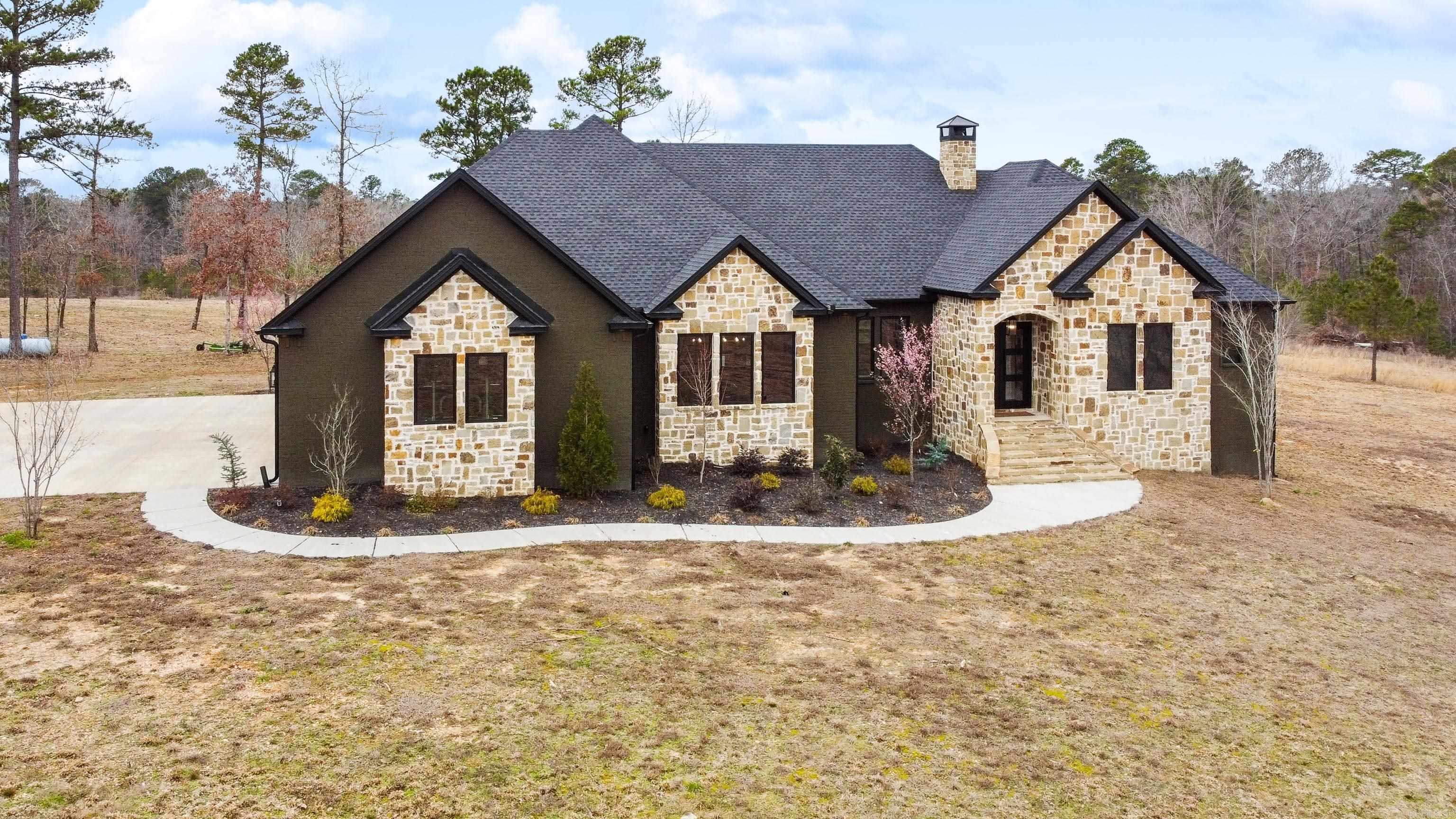 Discover this stunning custom-built estate nestled on over 22 acres just outside the city limits—where luxury meets serenity in a breathtaking natural setting. Boasting 3,072 sq. ft., this exquisite home is designed with vaulted ceilings, hardwood & tile flooring, 4 Bedrooms, 3.5 Baths, 3-Car Garage and custom features throughout. A chef’s dream with a custom island, double built-in ovens, gas stove, KitchenAid appliances, and walk-in pantry. Relax in your primary suite with a spa-like sanctuary featuring his & her vanities, a wet room, and a private toileting area. Enjoy the spacious elegance of an open floor plan, formal dining, and custom walk-in closets with ceiling pull-downs. A large safe room with a Browning door, just steps from the living area. Cozy up by the natural stone-covered wood-burning fireplace or retreat to the screened-in back porch with a second wood-burning fireplace. Additional highlights include zoned AC units, a spacious laundry room with space for a second fridge, tile showers throughout, foam-insulated attic access from the garage, and a private gated entrance. Don't miss your chance to own this extraordinary property! Schedule your private showing today!