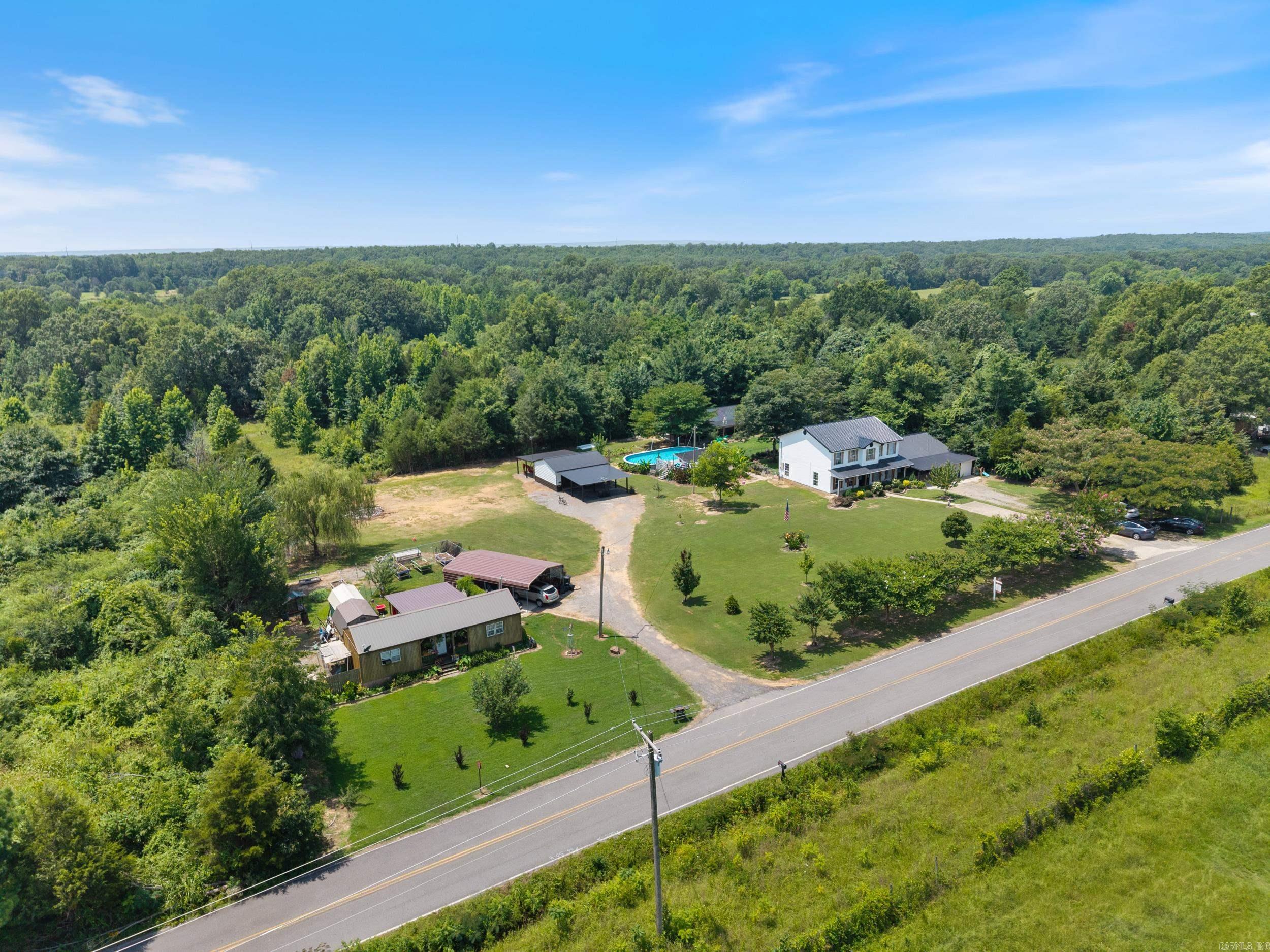 Beautiful 2-acre property with mature trees, open green space, and a sparkling swimming pool—perfect for relaxing or entertaining. This well-kept two-story home offers 3 bedrooms, 2.5 baths, formal dining, and a spacious, light-filled living area. The primary suite features a walk-in closet and private bath. Enjoy classic curb appeal with a covered front porch and durable metal roof. The property includes multiple electric meters serving the detached shop, finished tiny house, and a framed, unfinished structure with plumbing rough-in—offering potential for an ADU, guest space, or workshop. Convenient location with easy access to town, schools, and major highways.