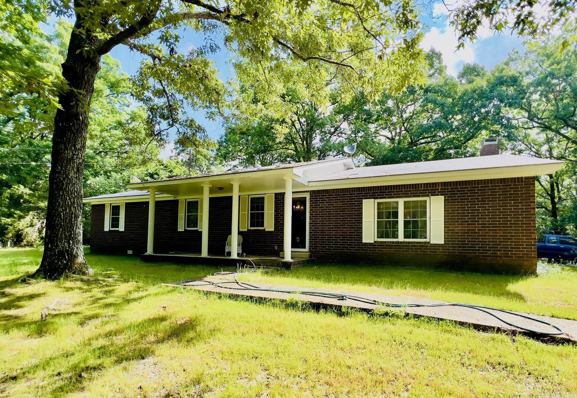 Spacious brick home with beautiful large shade trees in private location just off paved county road. You're going to love this 1922 sq ft home offering a large living area with brick accent wall, woodburning fireplace with insert and beamed ceiling. Well-arranged kitchen with ample cabinets and breakfast bar. Designated dining area, den, nice sized bedrooms, laundry room, roomy full bathroom, currently being updated. You'll appreciate both public water, well, natural gas, septic on property. Septic system inspected and pumped in 2025. Central Heat & Air 5 yrs old.  14x45 RV carport with slab, electric, dump station for convince .  18x30 shop with vehicle lift, spray insulation, heat & air.  Nice outbuilding with electric. Must see property.
