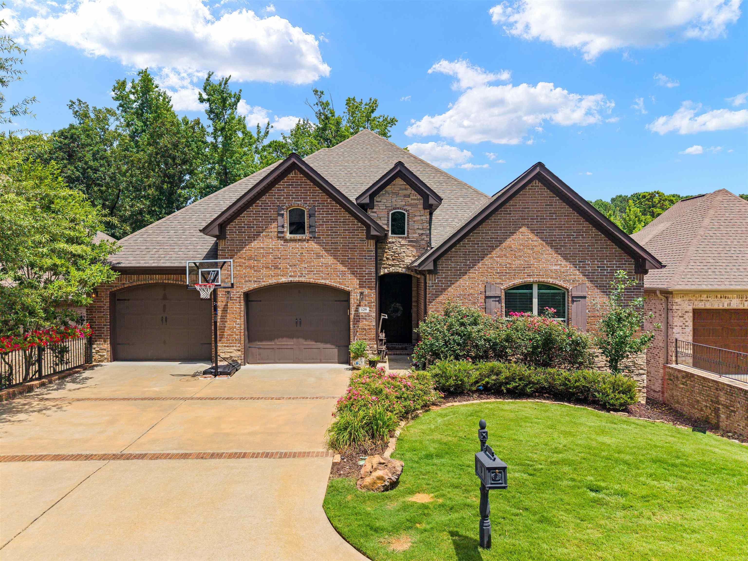 This immaculate 5 Bed, 4 Bath home is located in the beautiful Woodlands Edge of West Little Rock, offering access to scenic trails, fishing creeks, tennis courts, parks, and protected green space.  Inside, you're welcomed by tall ceilings and beautiful finishes throughout. The spacious living room features a stacked stone gas log fireplace and opens to a covered balcony with a second gas log fireplace, privately surrounded by lush greenery.  The functional floor plan keeps the primary suite tucked away with great views, a walk-in rain shower with seating, jetted tub, and walk-in closet.  The kitchen features a wraparound granite breakfast bar, farmhouse sink, built-in gas cooktop, convenient sliding corbels, and a walk-in pantry, opening into the spacious dining area.  Also on the main level are 3 guest bedrooms, 2 full baths, and a large laundry room with built-in lockers.  Take the stairs to your massive bonus room with a private bath and access to a second covered patio overlooking the flat, fully fenced backyard.  Don't miss the two easy-access crawl spaces, perfect for storage or a workshop.   We're excited for you to come see if it's yours!  129 Cove Creek Ct  Welcome home.