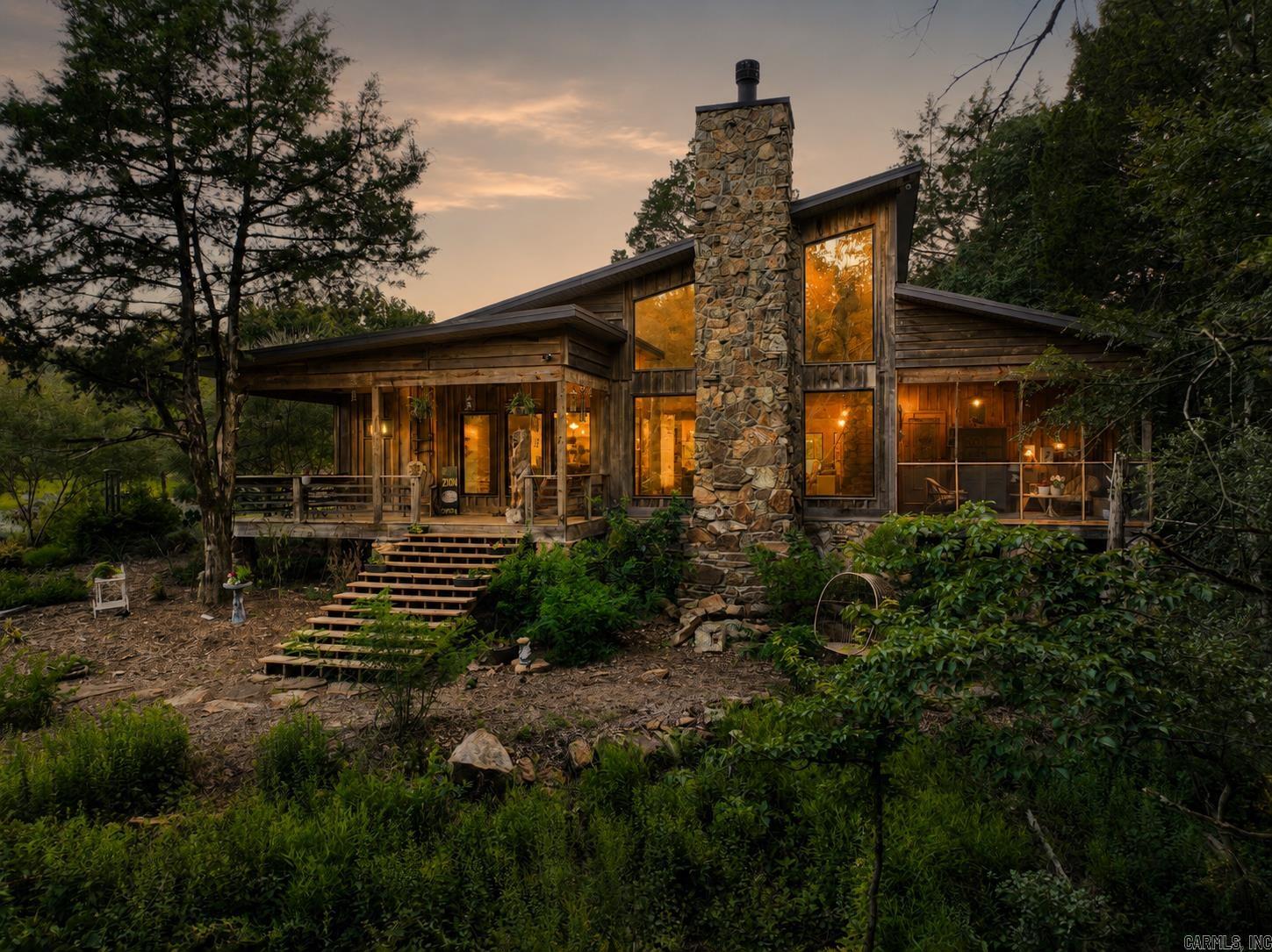 Absolutely stunning mid-century style lodge nestled in the middle of 5 private acres next to a gorgeous creek. You won't believe the peace and tranquility you'll find when you step into this home with 20' ceilings, open floor plan, natural light, gorgeous stone fireplace built with rock from White County, pine floors and beams all locally milled, all custom light fixtures from Poland and Slovenia, two living areas, custom kitchen cabinets and countertops with GE cafe appliances, and a loft for an office/playroom or music room. The primary suite features a custom tiled shower room, huge walk-in closet and a partially screened-in porch for sipping your coffee by the running water! The exterior is a mix of locally milled red and white oak. Other features include a spectacular mudroom, covered porches and don't forget the 30x40 shop with a separate wood-working room and steps leading upstairs to  1200 sq ft finished living space including a huge rec room with two bedrooms and a full bath all centrally heated & cooled. This stunning home was built with exceptional charm and intentional craftsmanship in every single room! Make your appointment to tour this breath-taking retreat today!