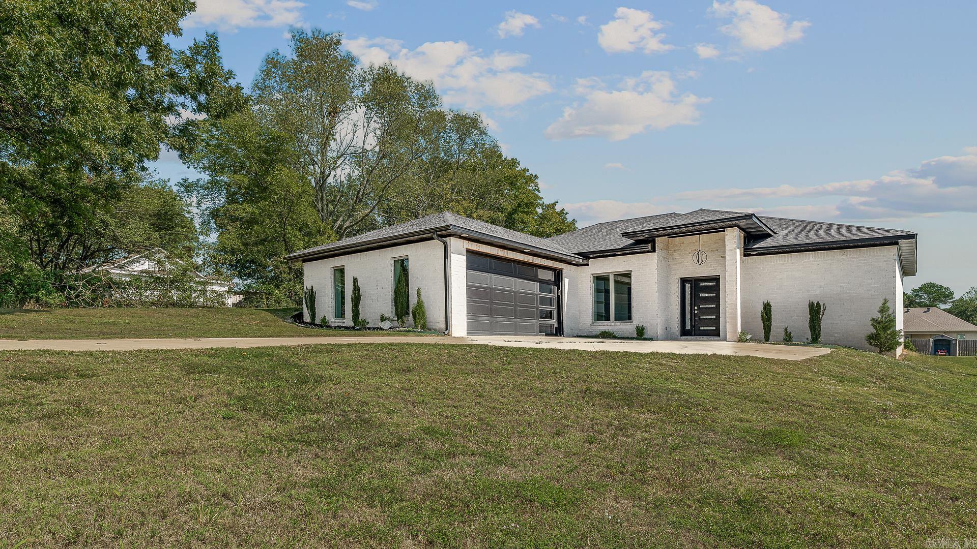 This beautifully designed all-brick home offers modern style, efficiency, and quality craftsmanship on a spacious  acre lot. Constructed with insulated concrete for durability and energy savings, the home features granite countertops throughout, stained concrete floors, and sleek modern fixtures that create a polished and contemporary feel.    The kitchen is complete with stainless steel appliances and abundant counter space, flowing seamlessly into the open living area accented by an electric fireplace. The primary suite includes a tiled shower and stand-alone soaking tub, offering a spa-like retreat within the home. With an all-electric design, fresh modern finishes, and plenty of outdoor space, this property combines low-maintenance living with everyday comfort.