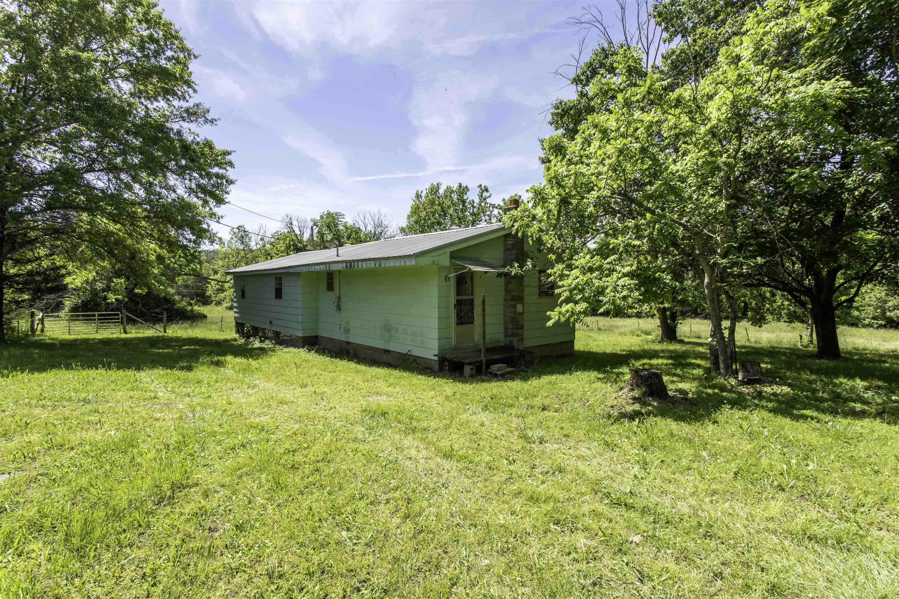 45-Acre Mini Farm with Well’s Creek, Fencing, Farmhouse & barn   Here’s the kind of property everyone keeps asking for: 45 acres with a 4-bed, 1-bath farmhouse, Well’s Creek meandering thru the property, perimeter fencing, utilities in place, and rural water available. Currently being utilized by a neighboring cattleman, this is already set up with real agricultural potential and offers the kind of head start that’s hard to find.  The land is well-suited for a mini farm, cattle operation, homestead, recreational retreat, or country getaway, with room for livestock, gardening, hunting, trails, or future improvements. The perimeter fencing adds immediate usefulness, while the creek brings natural beauty, water appeal, and that peaceful Ozark foothills feel buyers love. The farmhouse offers 4 beds and 1 ba, giving a solid country home base to renovate, restore, or use while building their dream setup. Features include a wood-burning stove and a metal roof installed in 2017, adding practical value and rustic charm. With power, water, creek frontage, fencing, pasture use, and a farmhouse, this property is more than acreage — it’s a working start toward the country lifestyle.