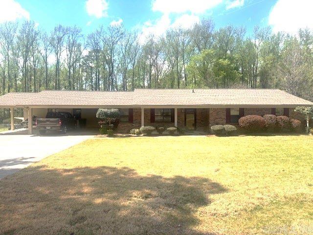 This inviting brick home makes a great first impression the moment you pull into the driveway. It features a two-car carport with additional space perfect for a golf cart, 4-wheeler, or bicycles. Inside, you’ll find a spacious living room with a cozy gas fireplace that flows into an adorable kitchen equipped with a newer dishwasher, electric range, and negotiable refrigerator, all set on attractive vinyl tile flooring. A beautiful den, added in 1998, offers even more living space, complete with a 2nd gas fireplace framed by built-ins, canned lighting, vaulted, beamed ceilings, & stunning wood floors. From here, step out onto the covered porch overlooking the fenced backyard, which includes two storage buildings for all your outdoor needs. The home offers two additional bedrooms served by a hall bath, while the primary bedroom includes its own private bath, a generous walk-in closet, and two additional closets for exceptional storage. Located on a non-thru street, you’ll enjoy minimal traffic and a peaceful setting. For summer fun, the neighborhood pool is available for relaxation and recreation. This home is truly a must-see. Schedule your appointment today!