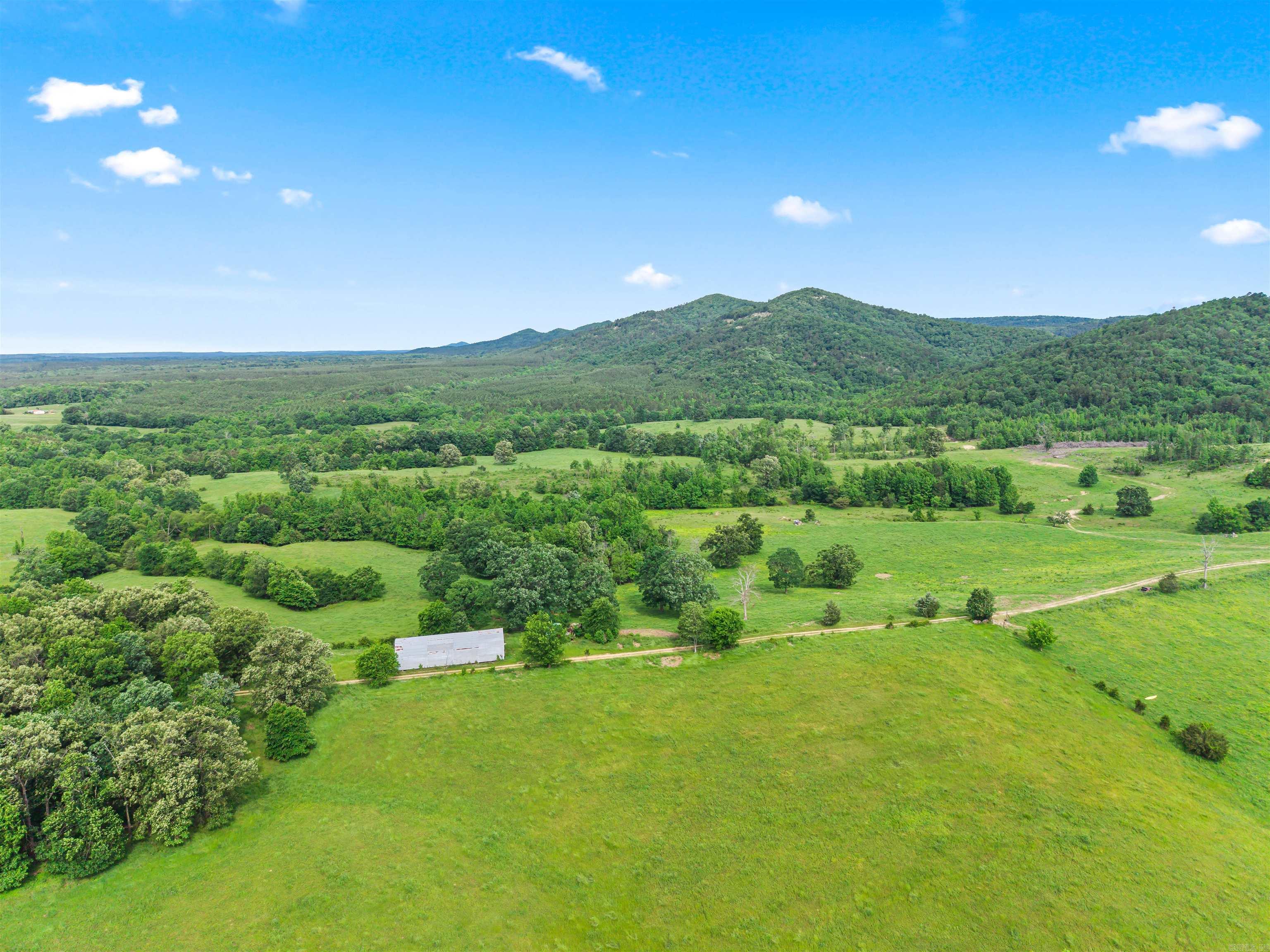 Rarely does a property this complete come to market. Located in the beautiful Lodi community, just 15 minutes from Glenwood in the Kirby School District, this 430± acre ranch borders the Ouachita National Forest and delivers the trifecta serious buyers demand — productive working ground, exceptional water, and spectacular views — all within a single boundary.  | THE LAND: Rolling pastures cross-fenced into multiple paddocks currently support 200+ head of cattle, with infrastructure in place to continue ranching from day one. Lush grass stands, mature scattered oaks for shade, and well-maintained interior roads make this a turn-key cattle operation. Multiple premium building sites — including two bluff-top locations with panoramic views of the Ouachita Mountains — invite the next owner to build a legacy home or hunting lodge without compromise.  | THE WATER: Self Creek, a year-round Ouachita Mountain stream with crystal-clear water running over a rocky gravel bottom, winds through the property with the seller owning both banks. A stocked pond adds a second water feature. In Pike County, year-round water of this quality is the most sought-after and hardest-to-replace asset a rural pr