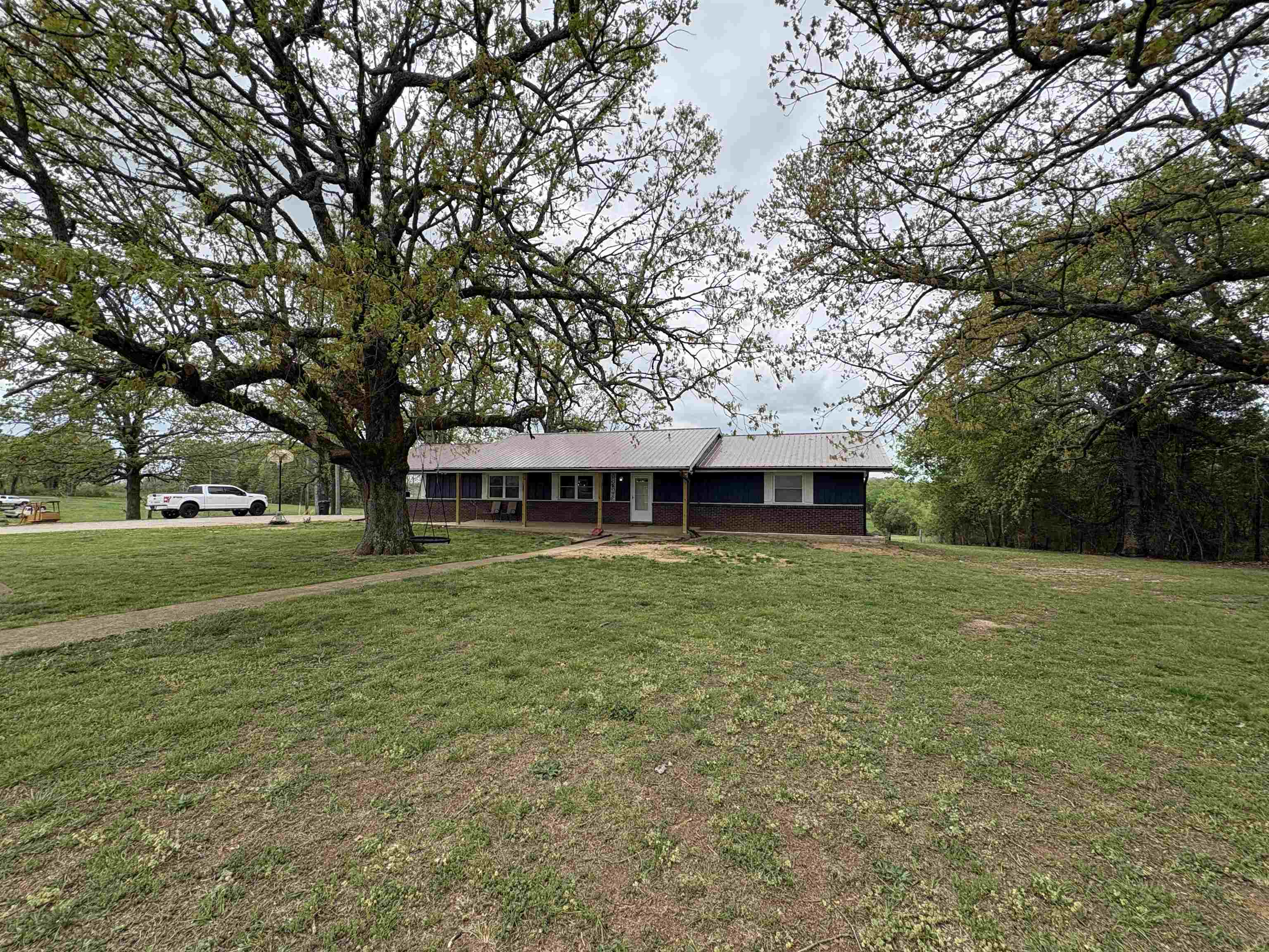 Sitting on 3.58 acres+/-, this 4 bed, 3 bath 3,160sqft home offers a wide-open yard and fenced backyard—ready for animals, room to roam, or simply enjoying your own space. Upstairs is bright, open, and inviting with beautiful wood trim, durable vinyl plank flooring, and a gas log fireplace that anchors the living space. The kitchen, dining, and living flow seamlessly together, with sliding doors leading to the back porch. Plenty of cabinet space, pantry, & stainless steel appliances. You’ll also find 3 bedrooms, 2 baths, and laundry all on the main level with 1,664sqft. Downstairs is where the possibilities open up. 1,456sqft of a full remodeled basement, it’s currently set up as a private primary suite with a walk-in shower, plus a massive second living area perfect for a game room, media space, or entertaining. A bar, utility sink, and walk-out access to the above-ground pool make it ideal for hosting or unwinding at home. Large two car garage, workshop space to hold your tools, beautiful mature trees, plus with the NEXT fiber optic Internet! Home is on city water and city sewer. Space, freedom, and a home that adapts to your life all with a scenic Ozarks setting!