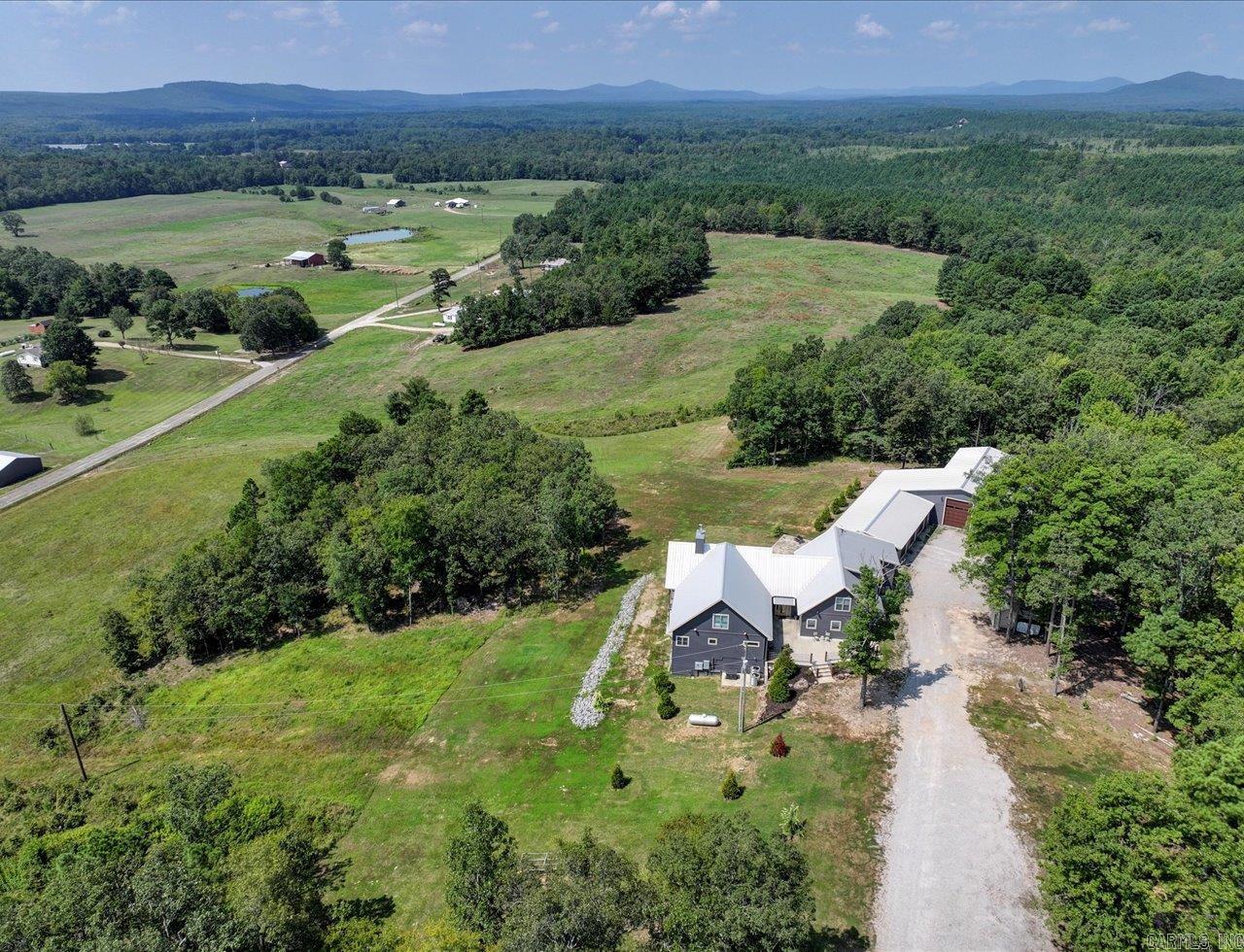 Custom-built home on approximately 23 acres in the Lake Hamilton School District with expansive views, stunning sunsets, and natural forest surroundings. Conveniently located near Lake Hamilton, Lake Ouachita, hiking trails, and mountain biking, this property offers privacy with easy access to outdoor recreation and Hot Springs amenities.  This 4-bedroom, 4.5-bath home features vaulted ceilings, an open-concept layout, two primary suites on the main level, two laundry rooms, a safe room, and a large game room ideal for entertaining or recreation. Built with 12-inch concrete walls, the home was designed for durability, comfort, and functionality.  Outdoor spaces include a deck and stone patio positioned to capture the scenic surroundings. Garage and workshop space are exceptional, featuring an attached 3-car garage, separate RV garage, approximately 2,761 sq. ft. of total garage space, and an 894 sq. ft. heated and cooled workshop. A whole-house generator adds convenience and reliability.  A rare opportunity to own a custom acreage property near lakes, trails, and Ouachita National Forest recreation.