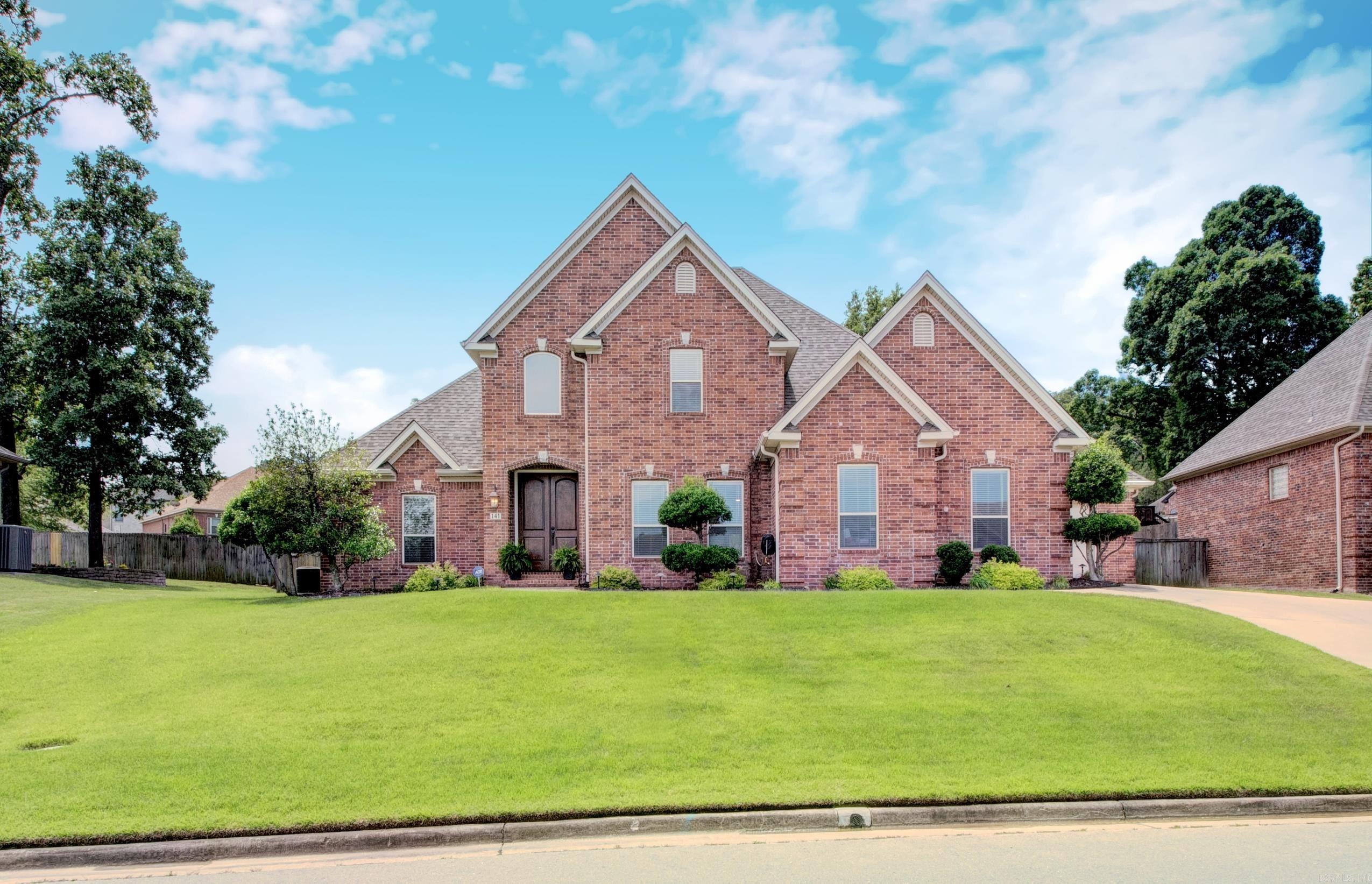 Beautiful custom-built home in Maumelle Valley Estates, originally built by the builder for his personal residence and purchased prior to occupancy—reflecting quality craftsmanship and thoughtful design. This well-maintained home offers 4 bedrooms and 3.5 baths, including two primary suites—one on the main level and a second upstairs with its own dedicated private bath. The spacious living area features custom built-ins surrounding a gas-log fireplace. Hardwood flooring enhances the grand foyer with custom chandelier and staircase, flowing into the formal dining area. The kitchen offers an island, maple cabinetry with glass accents, granite countertops, and stainless steel appliances. A private office with glass French doors is located just off the breakfast area. Upstairs includes the second primary suite with dedicated bath, two generously sized guest bedrooms, and a separate guest bath with dual vanities. A 3-car garage, front and back sprinkler system, French drains, and a 6-year-old roof complete the home. Enjoy outdoor living with a covered patio, extended flagstone patio, and additional seating area perfect for relaxing or a fire pit area.  Immaculate Condition!