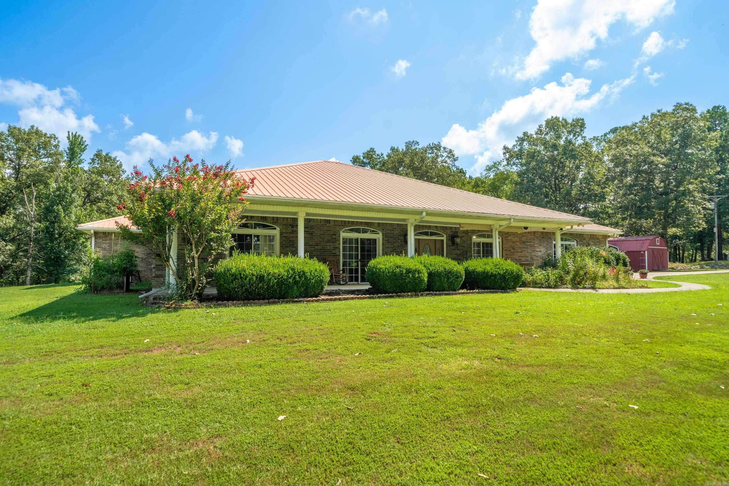 Beautiful custom-built home on 4.28 acres just outside Arkadelphia! With over 2,700 square feet, this home offers 3 bedrooms, 2.5 bathrooms, and plenty of space to spread out. The step-down living room with gas log fireplace and vaulted ceilings is warm and inviting while the large kitchen has lots of cabinets, a center island with a gas cooktop, and plenty of room for cooking and gathering. The dining area features a curved wall of windows that lets in lots of natural light and overlooks the covered patio. Spacious primary bedroom includes a huge bathroom with a corner tub and separate shower. Sitting on 4.28 peaceful acres, this property gives you room to enjoy the outdoors while still being just minutes from everything Arkadelphia has to offer. 2 car garage and detached carport. Outdoor storage buildings with electric. If you're looking for a well-built home with plenty of space inside and out, this one is worth a look! (outdoor bar does not convey)
