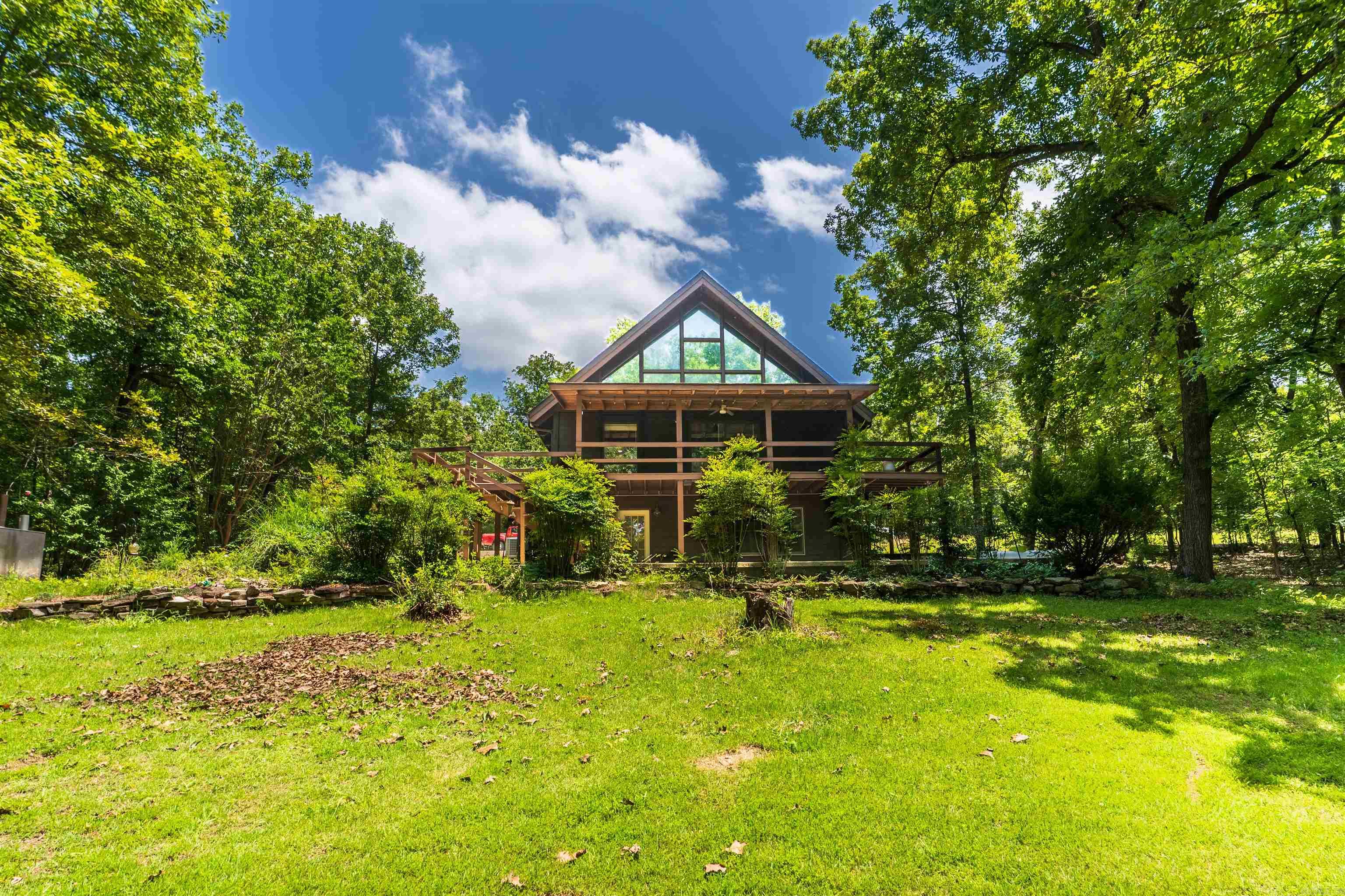 Stunning multi-level contemporary home in Cherokee Village! This beautifully updated 4-bedroom, 2.5-bath home offers approximately 2,300 SqFt of thoughtfully designed living space on a landscaped 0.30-acre lot. Inside, you'll find soaring vaulted ceilings, an open-concept layout, and a fully remodeled kitchen featuring slow-close cabinetry, a large island, tile backsplash, and breakfast bar. Appliances include a KitchenAid all-in-one microwave.   Recent updates include knotty alder doors and trim, fresh paint, LED lighting, ceiling fans, and a water softener. Roof and the AC unit are relatively new (2022). Both bathrooms have been tastefully renovated with modern finishes, including a luxury smart toilet. Flexible living spaces include a home office, den, guest room, storage area, and a spacious bonus/game room. Enjoy the beautifully landscaped yard, outdoor wood boiler, and all that Cherokee Village has to offer. Schedule your private showing today!