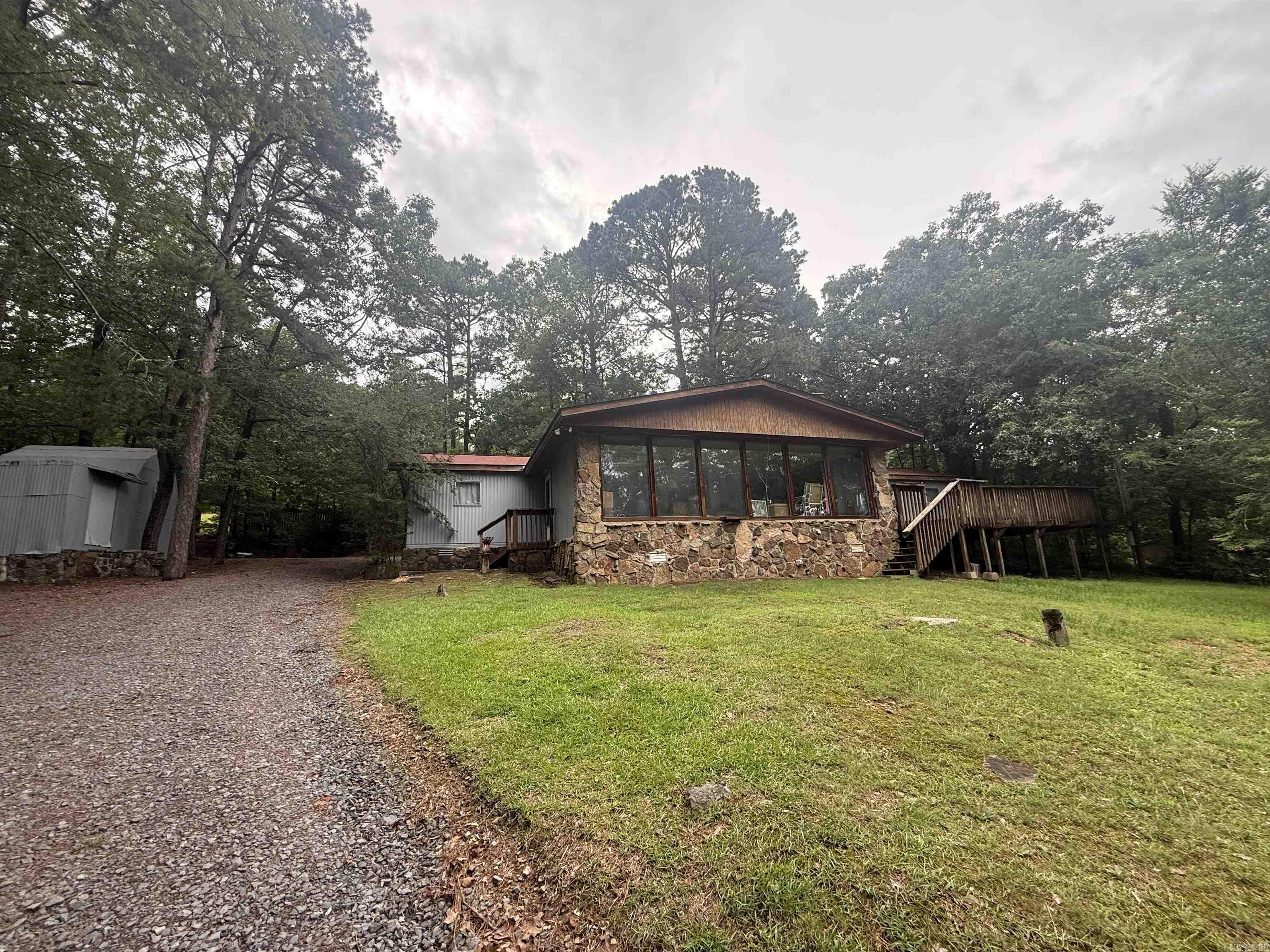 Welcome to your weekend lake house!  Partially furnished mobile home with a large additional living area/party room/sunroom/bunkroom...however you choose to use it!  Also has a large wood deck for relaxing and hanging out.  You can even sneak a peak of Greers Ferry Lake through the trees.  Located in a quiet neighborhood but just minutes away from all of the great restaurants and most importantly, Greers Ferry Lake and Devils Fork Boat Launch is just 3 miles away. Roof is less than 10 years old and hot water heater is 3 years old. Seller is leaving the appliances, sofas, recliners, and outdoor furniture. There is also an outdoor storage shed for lake toys.