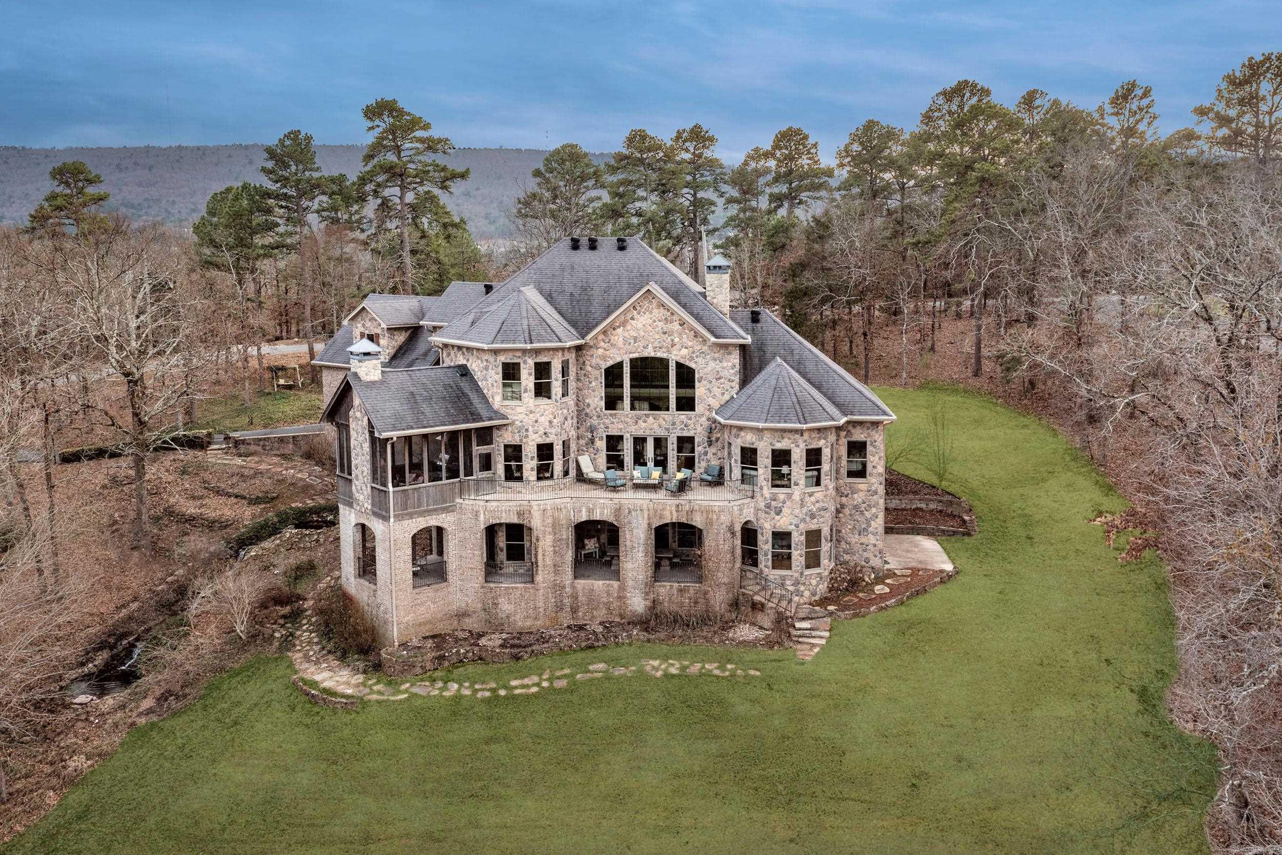 Stunning custom-built Old World European estate on 5 private cul-de-sac acres with breathtaking Pinnacle Mountain views. This 5-bedroom, 4-bath home offers over 6,700 sq. ft. of luxury living with geothermal heating and cooling, foam insulation, on-demand hot water, and a fire suppression system. Exceptional craftsmanship includes exposed wood beams, extra-wide oak floors, alder cabinetry, custom built-ins, and rich wood finishes throughout. The gourmet kitchen opens to spacious living areas filled with natural light from Pella wood-clad windows. The walk-out lower level features polished concrete floors, a bar, wine cellar, workshop, abundant storage, and a FEMA-rated safe room. Outdoor amenities include stamped concrete patios, a screened porch with fireplace, gazebo, vineyard, irrigation, brick-and-rock exterior with cedar accents, automatic shades, exterior lighting, and generator hookup. Offering privacy, spectacular views, and timeless design just minutes from West Little Rock, this one-of-a-kind estate is truly exceptional. Schedule your private showing today.
