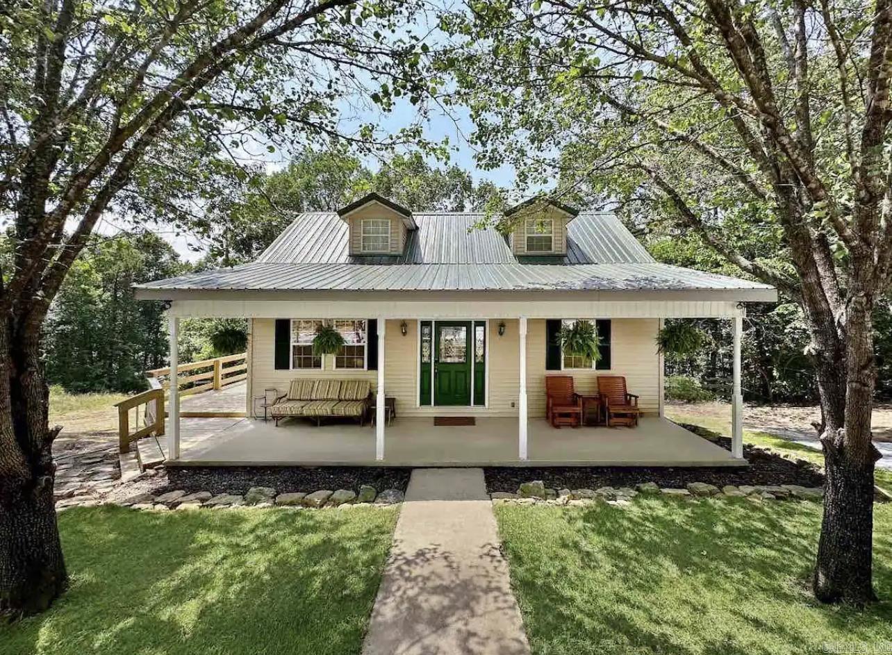 Looking for a lake getaway? This charming 3-bedroom, 1.5-bath home sits on a 1-acre lot just steps from Greers Ferry Lake, offering peaceful winter water views and easy access to a quiet boat launch about 2 miles away on Ramp Lane. The spacious wraparound deck and cozy front porch provide plenty of outdoor living space, while the newly landscaped yard includes extra parking pads for your boat and trailer. The main floor features a primary bedroom with a full bath, and two guest rooms upstairs share a half bath. With an 9-year-old metal roof, luxury vinyl flooring, and a new HVAC system, this well-maintained 2-story home is currently a successful vacation rental, making it a fantastic opportunity for a vacation rental or your own private retreat.