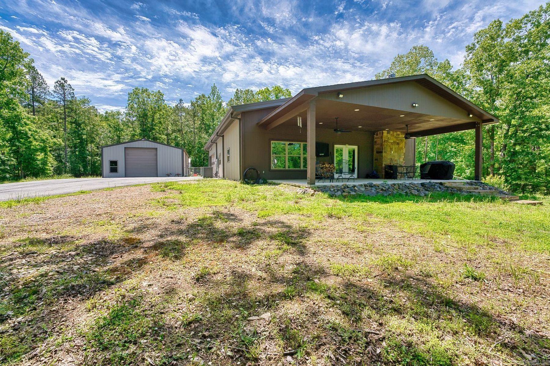 7 acres of private woodland yet just 10 minutes from town. This 2-bedroom, 2-bath barndominium blends modern luxury with rustic charm and features an open-concept gourmet kitchen with custom cabinetry, granite countertops, and a large island bar. The expansive living room offers soaring ceilings, a cozy fireplace, and picturesque forest views. Designed for efficiency it has 6-inch exterior walls with R-29 insulation, a tankless water heater, and a 22kW whole-home generator. The 2-car garage leads into a spacious mudroom/pantry and laundry room.     Outdoor living is a breeze on the massive covered porch overlooking the serene landscape.   Enjoy the 30x40 shop, complete with a restroom and a dedicated hobby room—ideal for woodworking, creative projects, or equipment storage. This property offers a rare combination of serenity, high-end craftsmanship, and city conveniences.